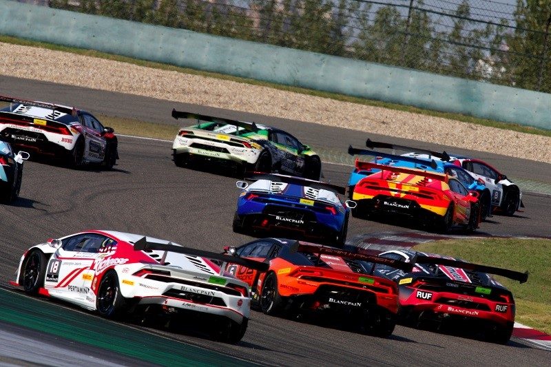 Multiple Lamborghini Huracán Super Trofeo race cars in colorful liveries battling through a corner at the Shanghai International Circuit