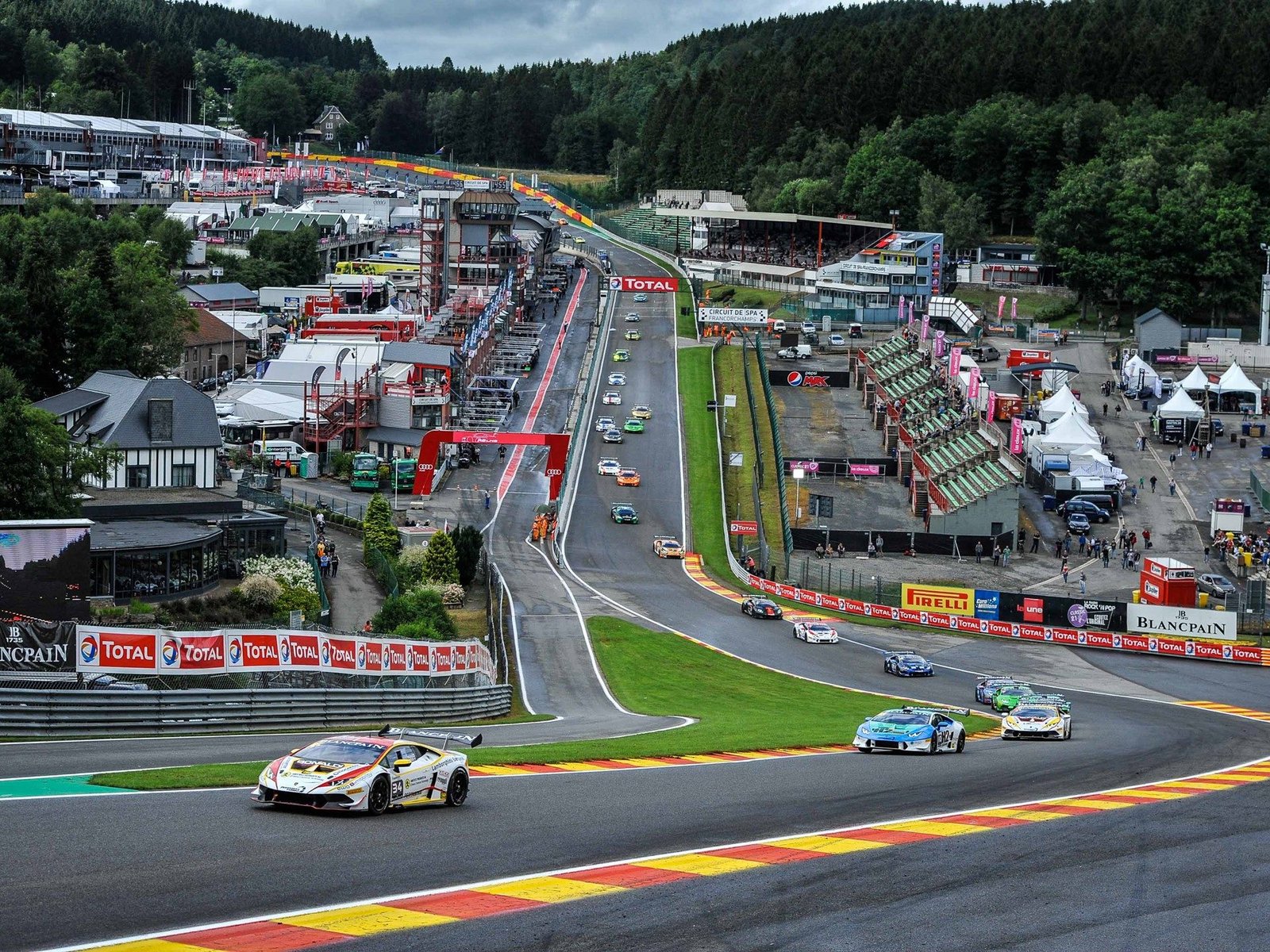 Aerial view of multiple Lamborghini Huracán Super Trofeo race cars battling through a corner at Spa-Francorchamps during the 2016 Blancpain Super Trofeo Europe