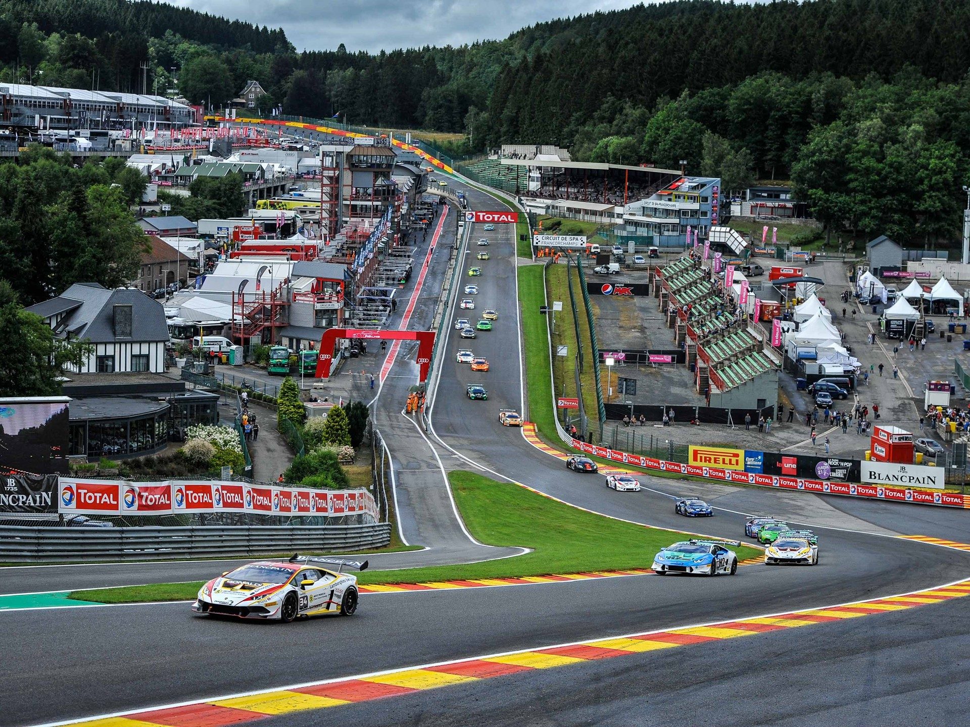 Aerial view of multiple Lamborghini Huracán Super Trofeo race cars battling through a corner at Spa-Francorchamps during the 2016 Blancpain Super Trofeo Europe