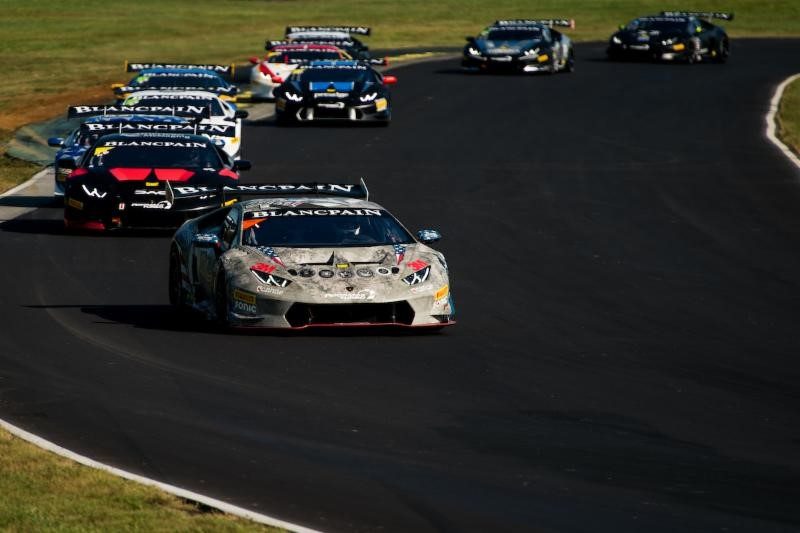 A pack of Lamborghini Huracán race cars battling through a corner at VIRginia International Raceway under bright skies
