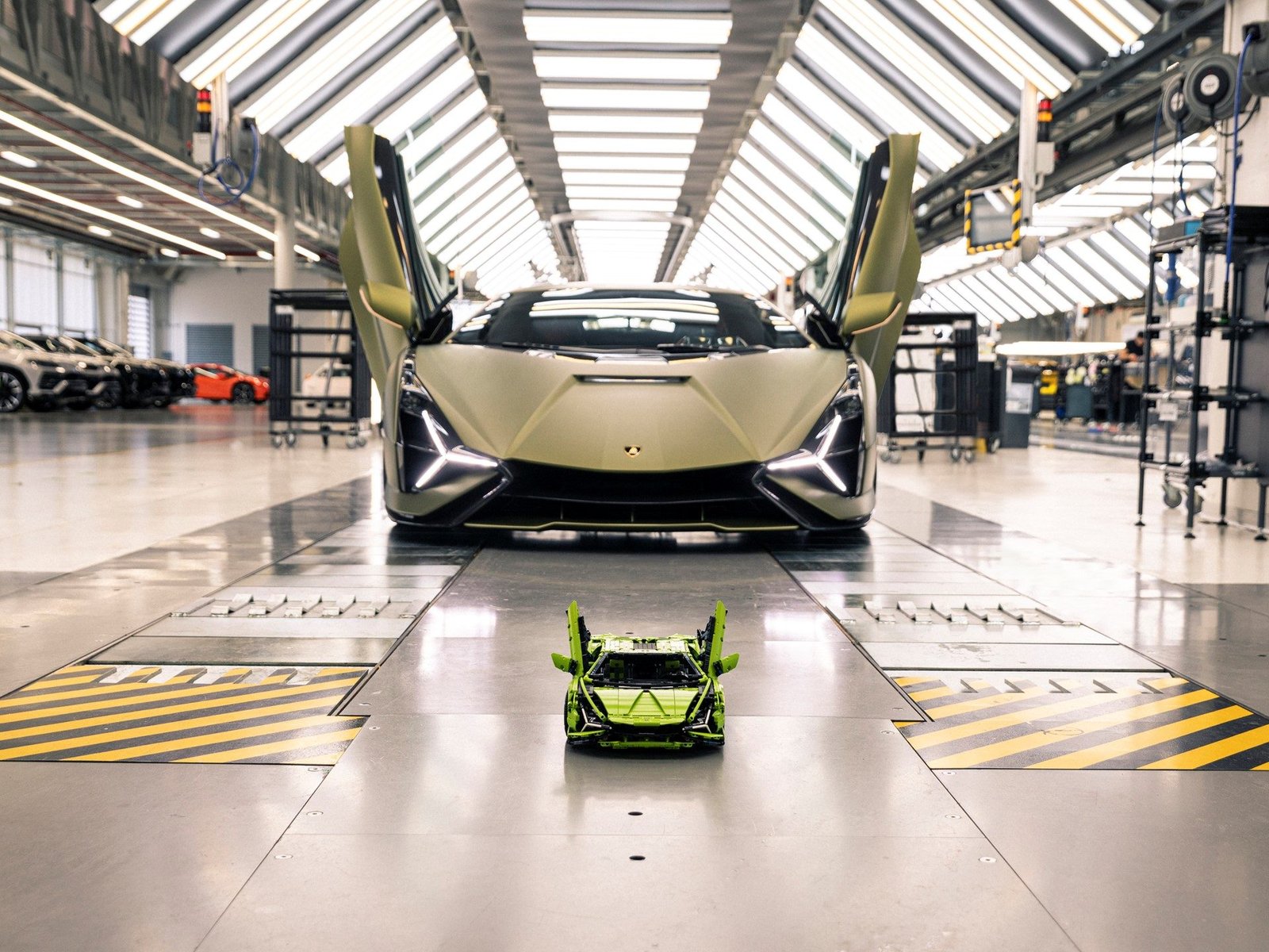 Full-size Lamborghini Sián FKP 37 with scissor doors open next to the LEGO Technic 1:8 scale replica on a factory floor