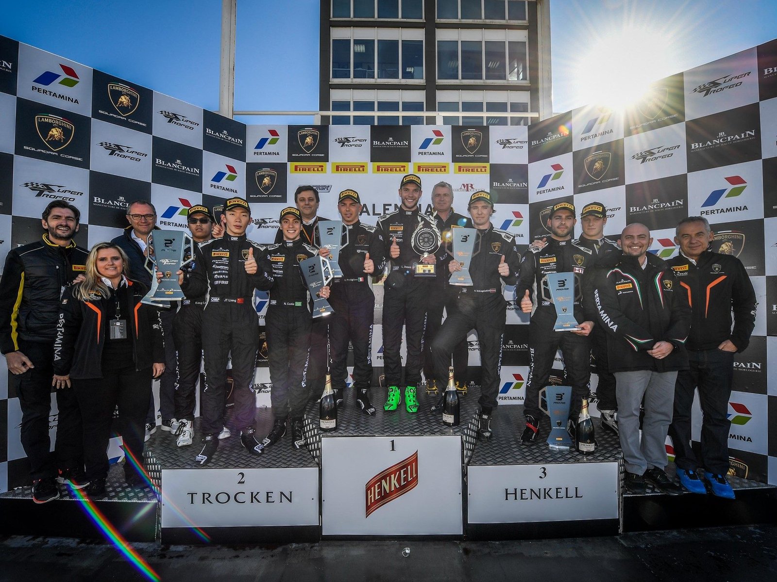 Lamborghini Blancpain Super Trofeo podium celebration with drivers holding trophies and champagne bottles