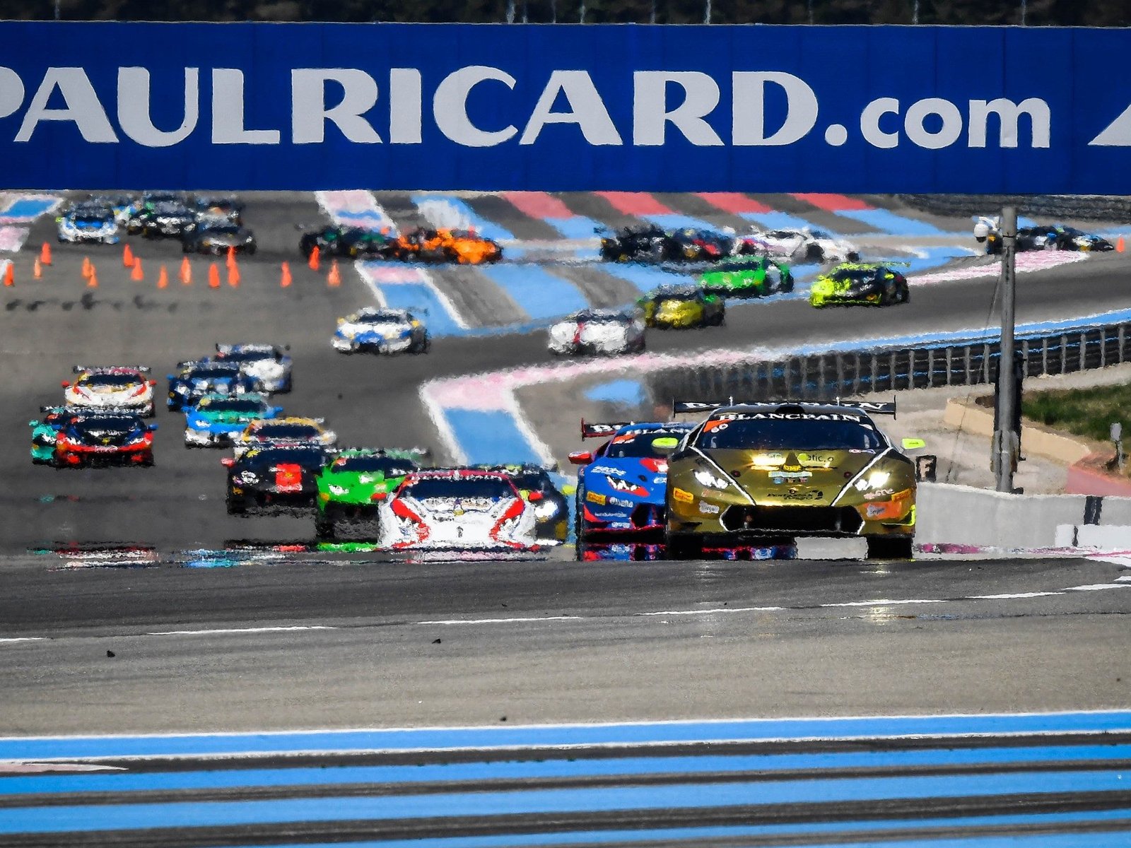 Lamborghini Huracán Super Trofeo race cars in close competition on the Paul Ricard circuit with carbon fiber aero elements and large rear wings visible