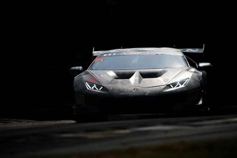 Grey Lamborghini Huracán Super Trofeo race car on track with headlights illuminated