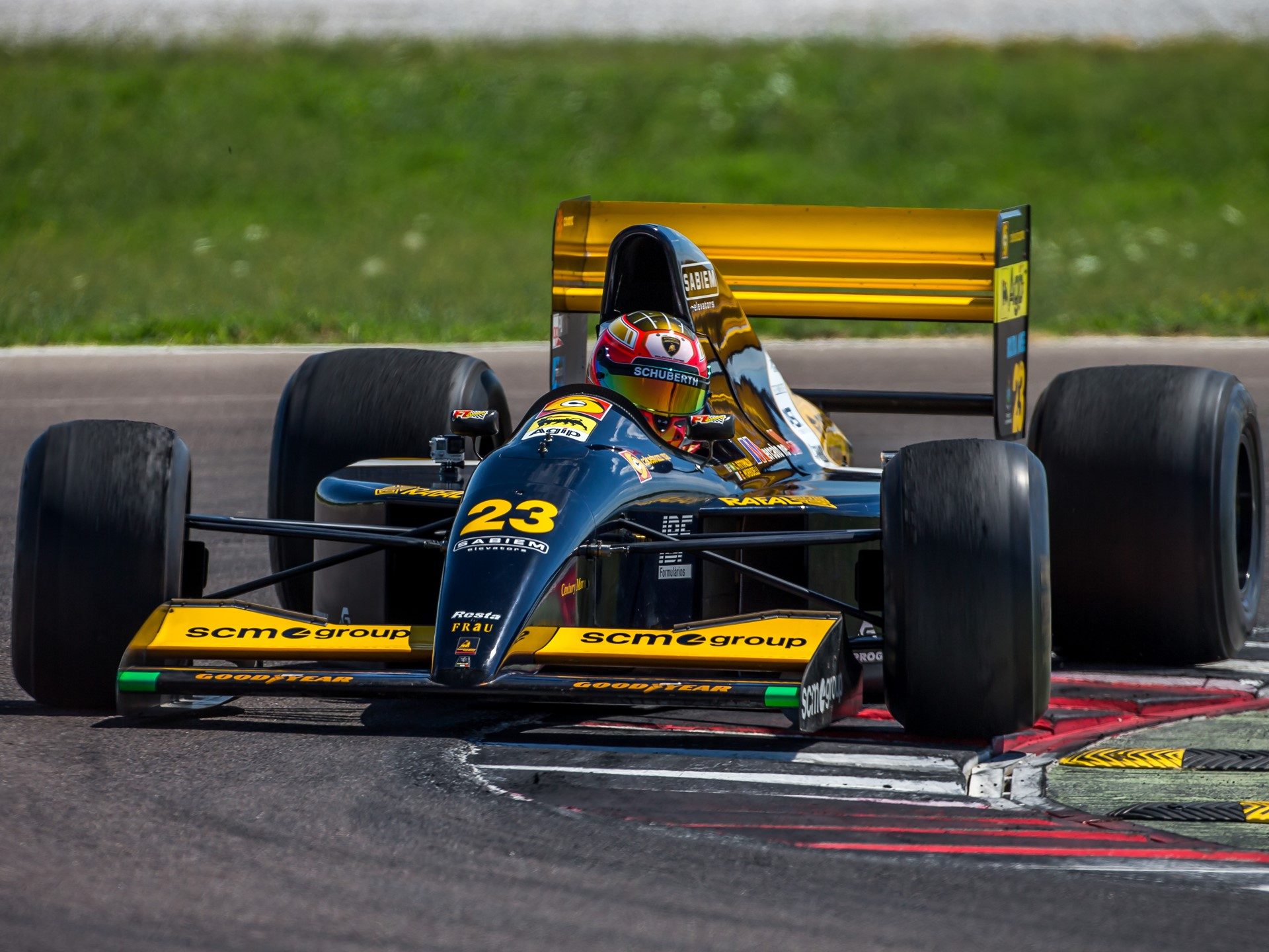 Restored Minardi M191B Formula 1 car with Lamborghini LE3512 V12 engine on track in black and yellow livery