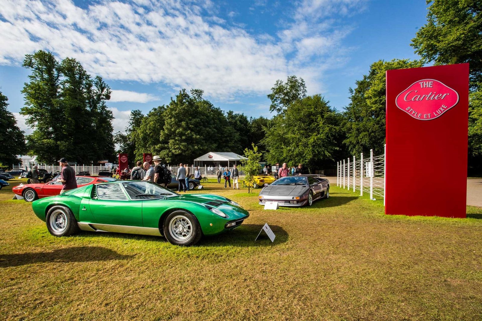 A vibrant green Lamborghini Miura displayed on the lawn at Goodwood Festival of Speed, with a Lamborghini Diablo visible behind it and spectators walking among the cars.