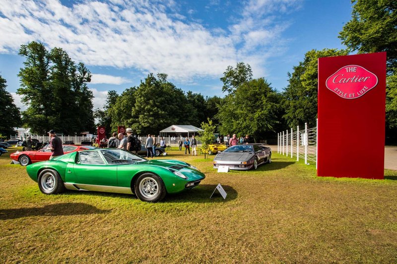 A vibrant green Lamborghini Miura displayed on the lawn at Goodwood Festival of Speed, with a Lamborghini Diablo visible behind it and spectators walking among the cars.