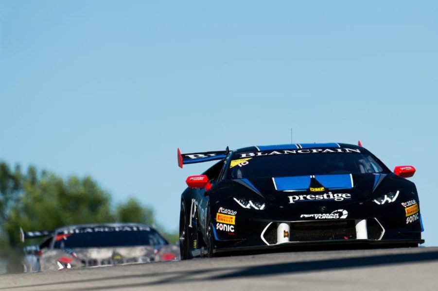 Black Lamborghini Huracán LP 620-2 Super Trofeo race car with blue and red livery racing at speed on track