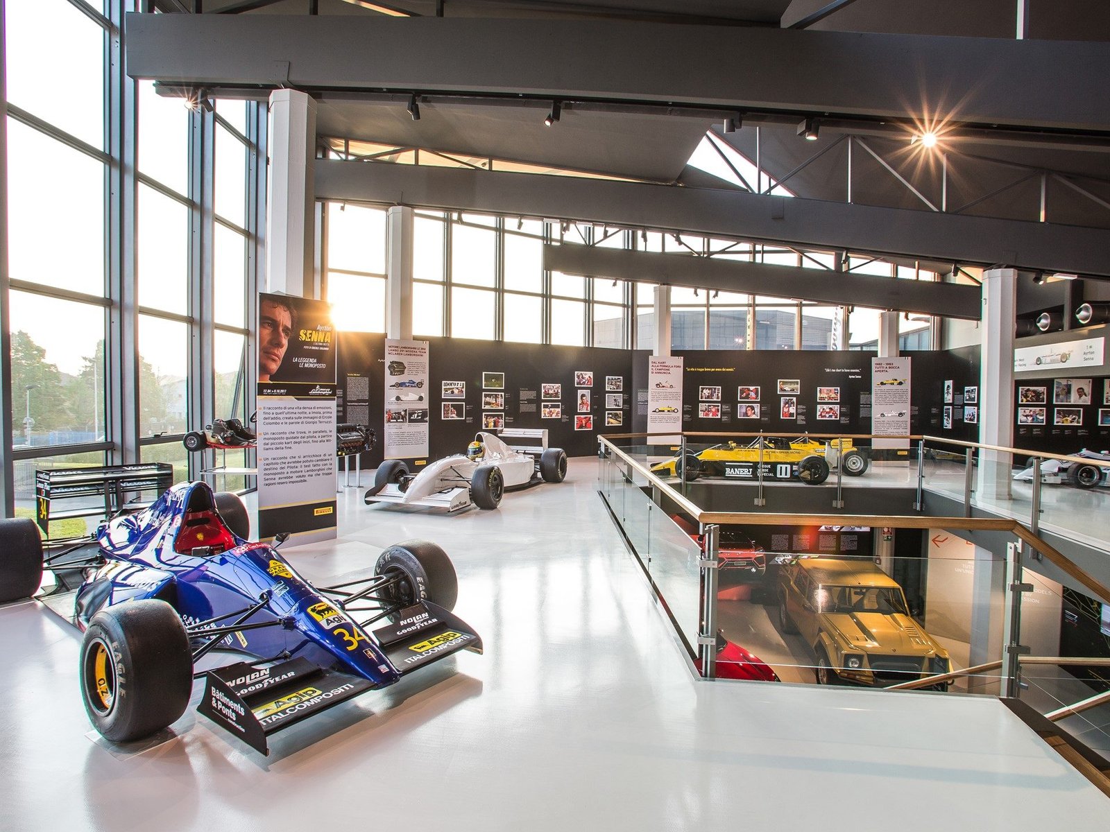 Exhibition hall at the Lamborghini Museum showing Formula 1 cars from Senna's career alongside a yellow LM002 and Senna portrait