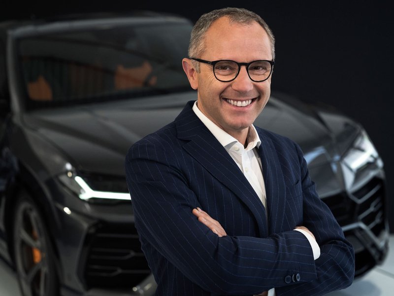 Stefano Domenicali, former Chairman and CEO of Automobili Lamborghini, standing with arms crossed in front of a Lamborghini Urus