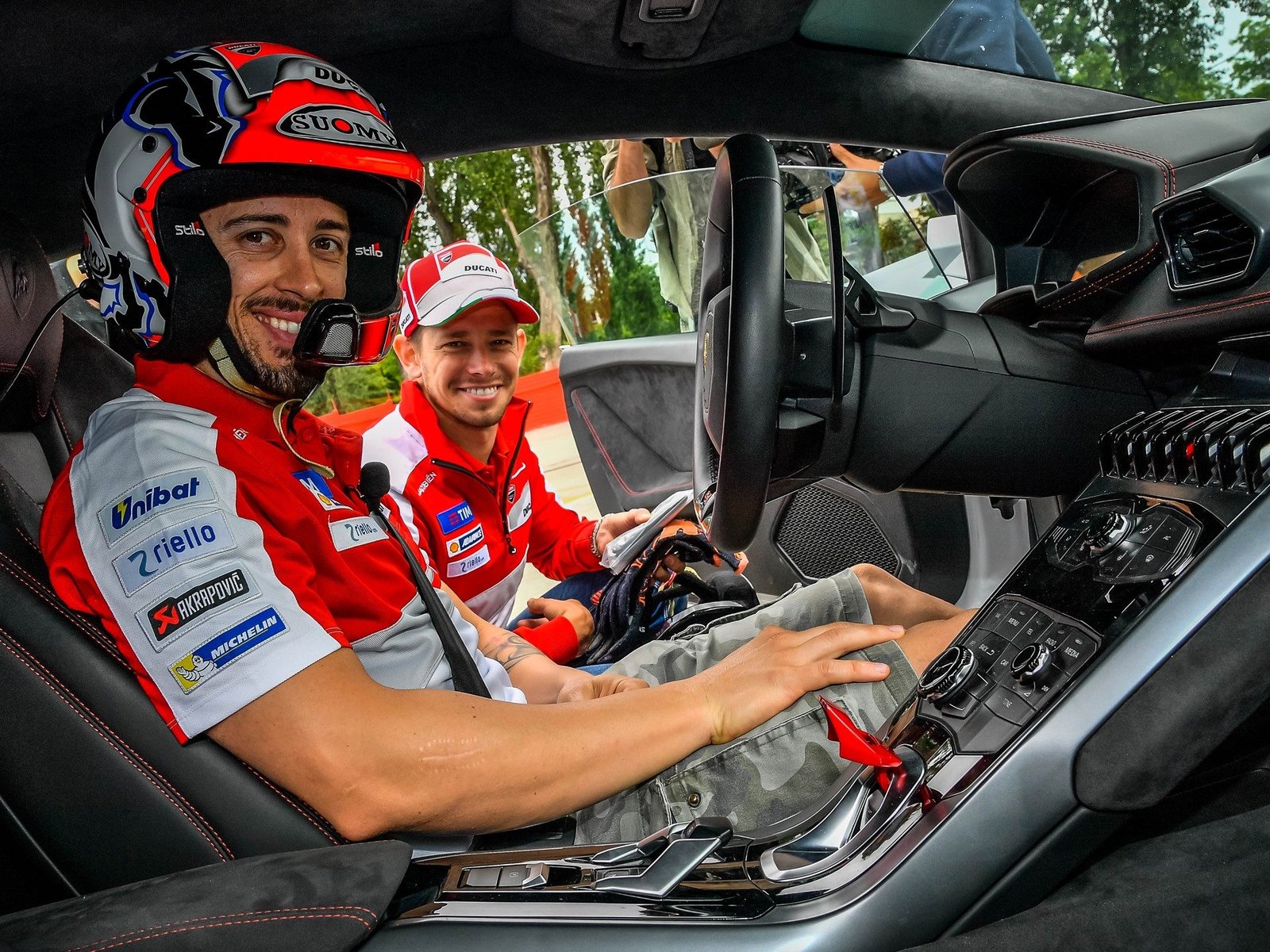 Casey Stoner and Andrea Dovizioso seated inside a Lamborghini Huracán cockpit at the Track Academy at Imola