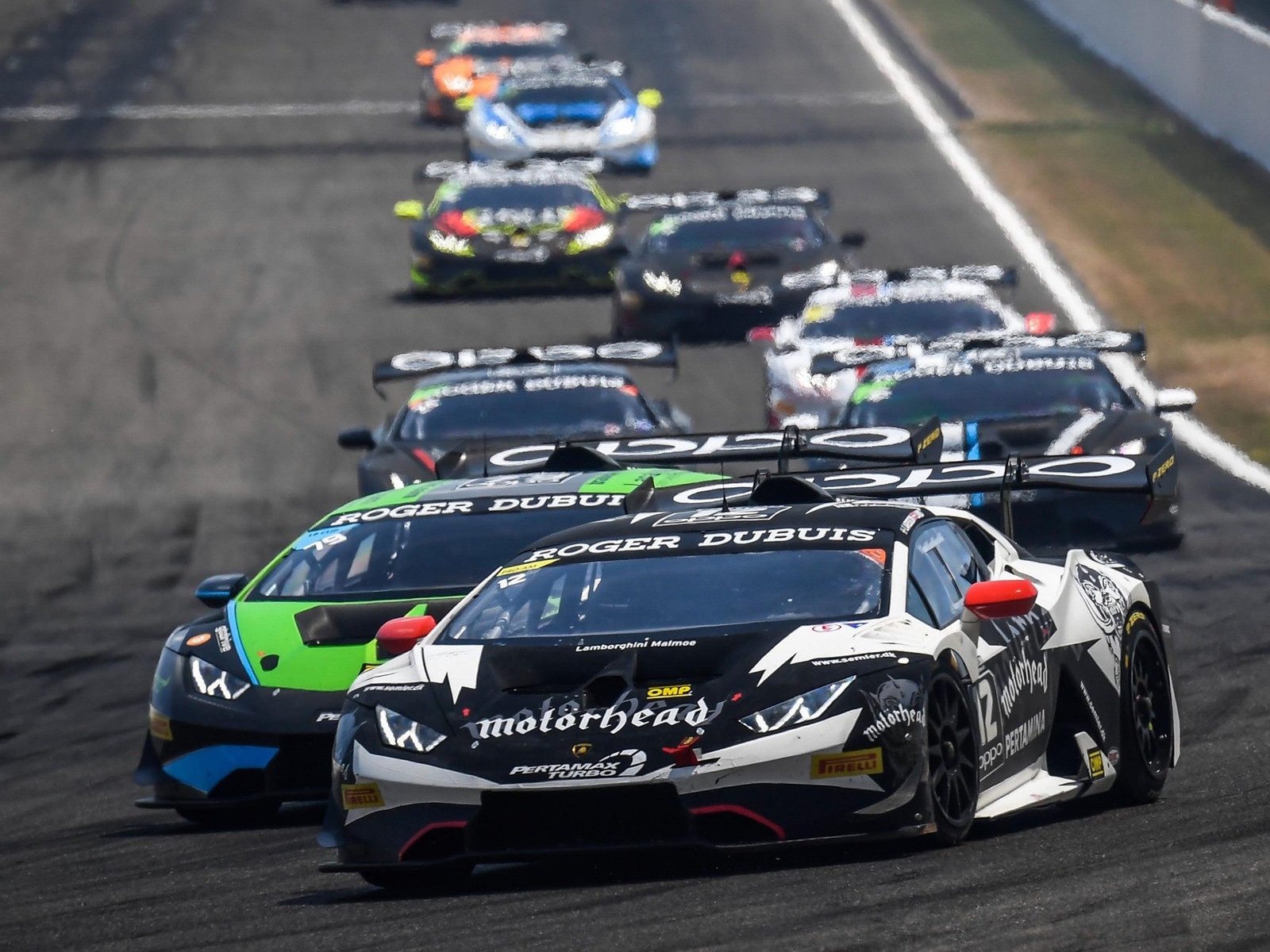 Multiple Lamborghini Huracán Super Trofeo race cars battling on track with aggressive aero and racing liveries