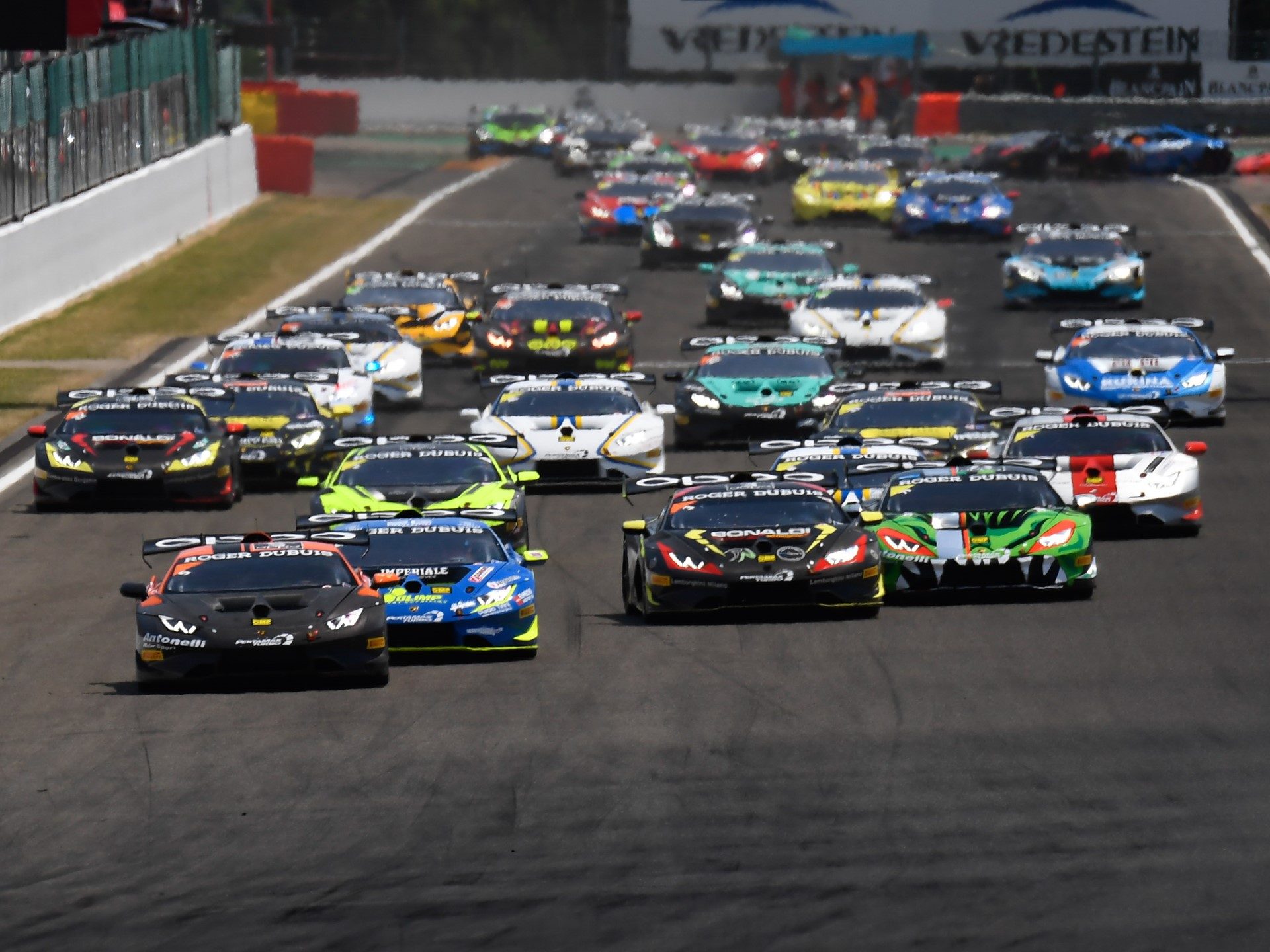 Multiple Lamborghini Huracán Super Trofeo race cars in various liveries battling for position on track during the Super Trofeo Europe round at Spa-Francorchamps