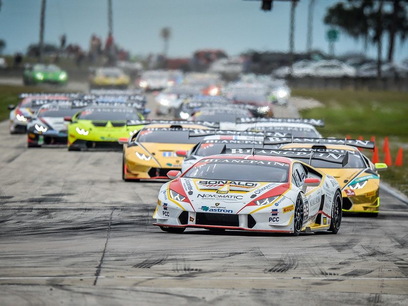 Lamborghini Huracán Super Trofeo race cars in close formation on track, showing aerodynamic body kits and large rear wings