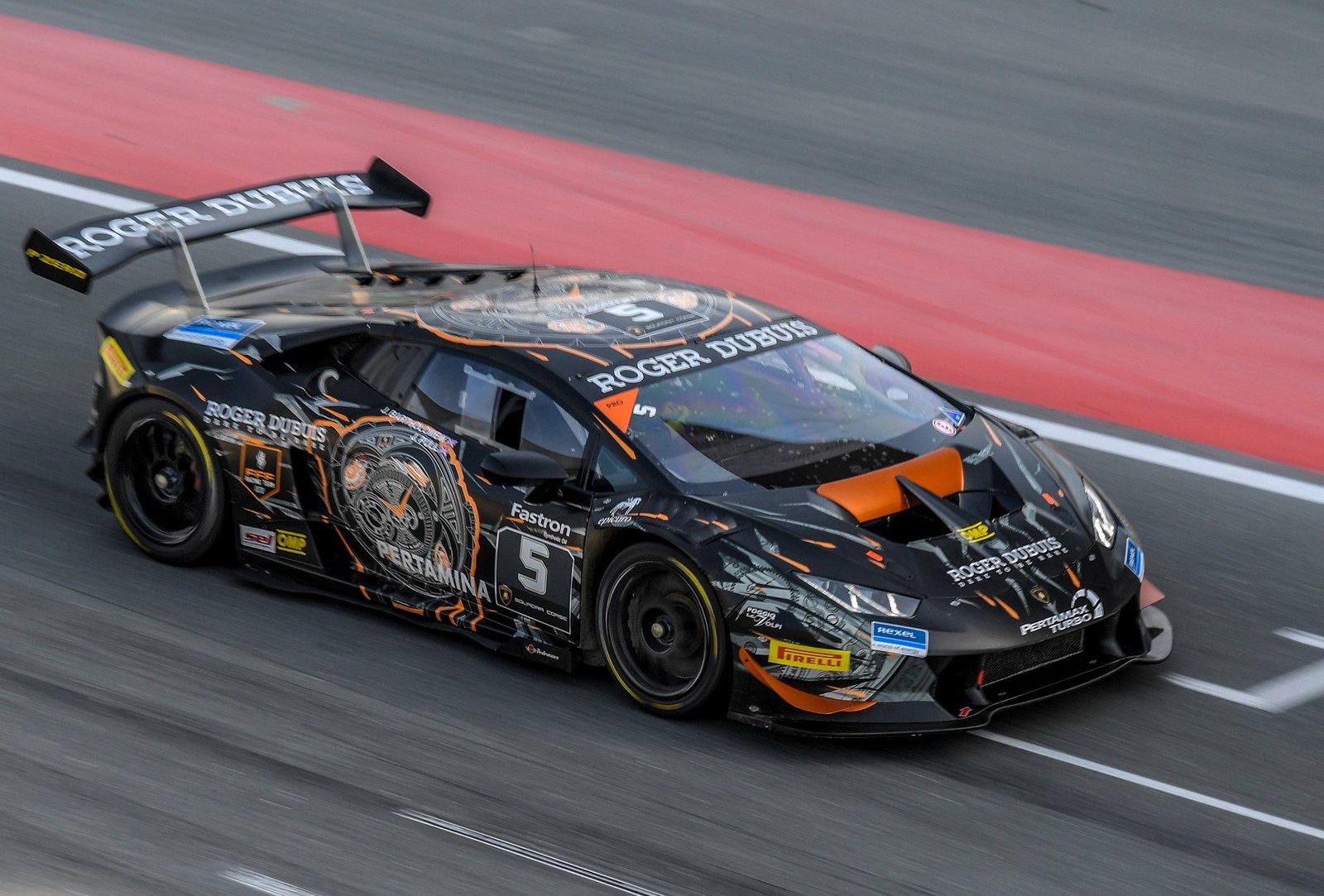 Black and orange Lamborghini Huracán Super Trofeo race car at speed on the Dubai Autodrome with motion blur