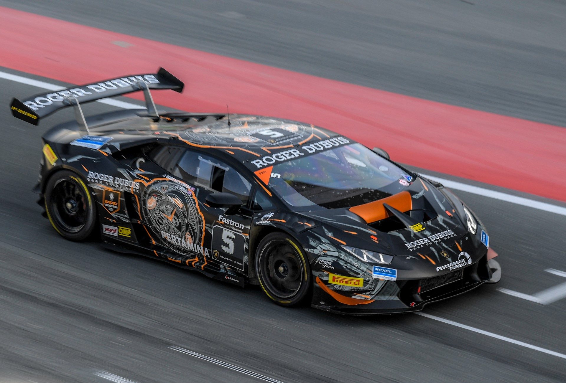Black and orange Lamborghini Huracán Super Trofeo race car at speed on the Dubai Autodrome with motion blur