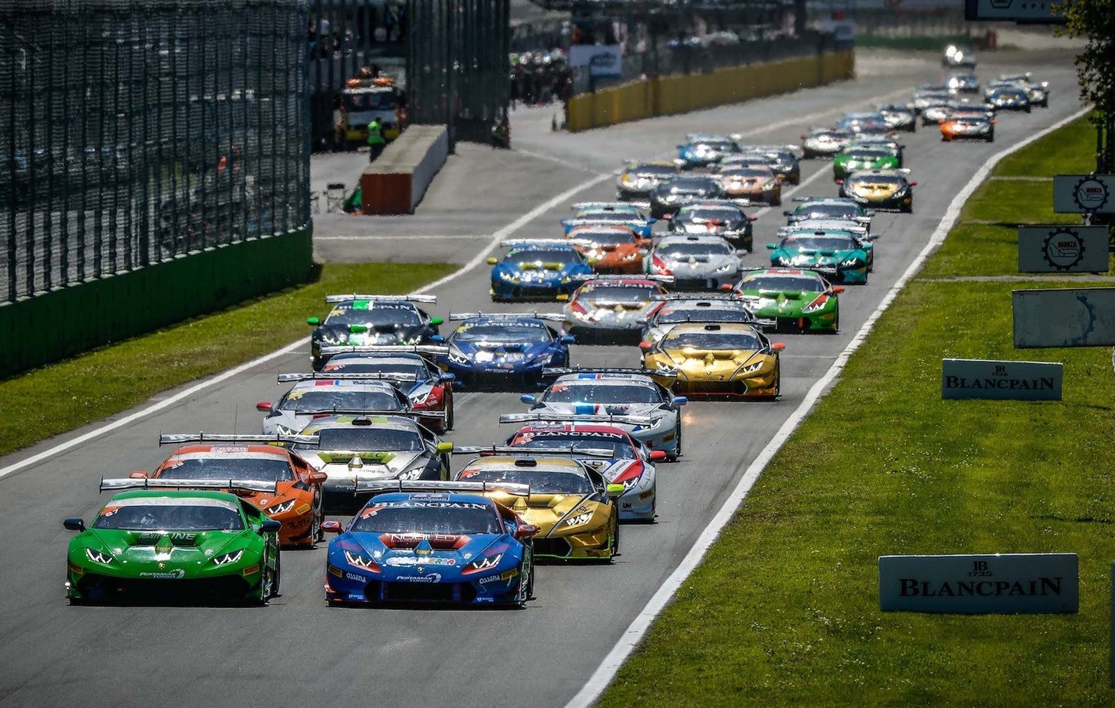 A packed grid of Lamborghini Huracán Super Trofeo race cars in various racing liveries jostling for position at Monza