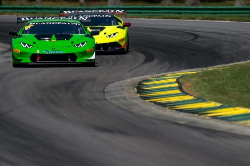 Two Lamborghini Huracán Super Trofeo race cars, one green and one yellow, battling through a turn during a Blancpain Super Trofeo event