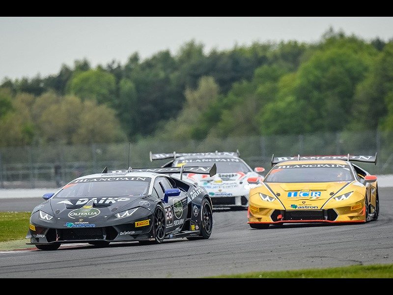 Three Lamborghini Huracán Super Trofeo race cars battle for position on a circuit, showcasing the intensity of the one-make series.