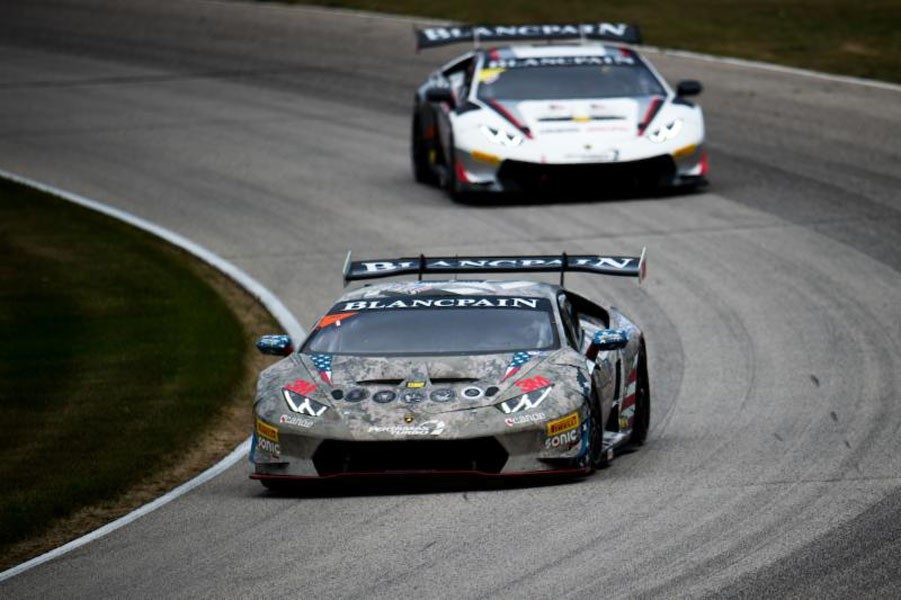 Two Lamborghini Huracán Super Trofeo race cars in close formation on the Road America circuit, showing aerodynamic body kits and racing slicks