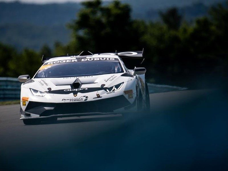White Lamborghini Huracan Super Trofeo EVO race car with black and yellow accents racing at speed on track