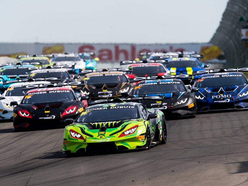 A pack of Lamborghini Huracán Super Trofeo EVO race cars in various liveries racing wheel-to-wheel at Watkins Glen International