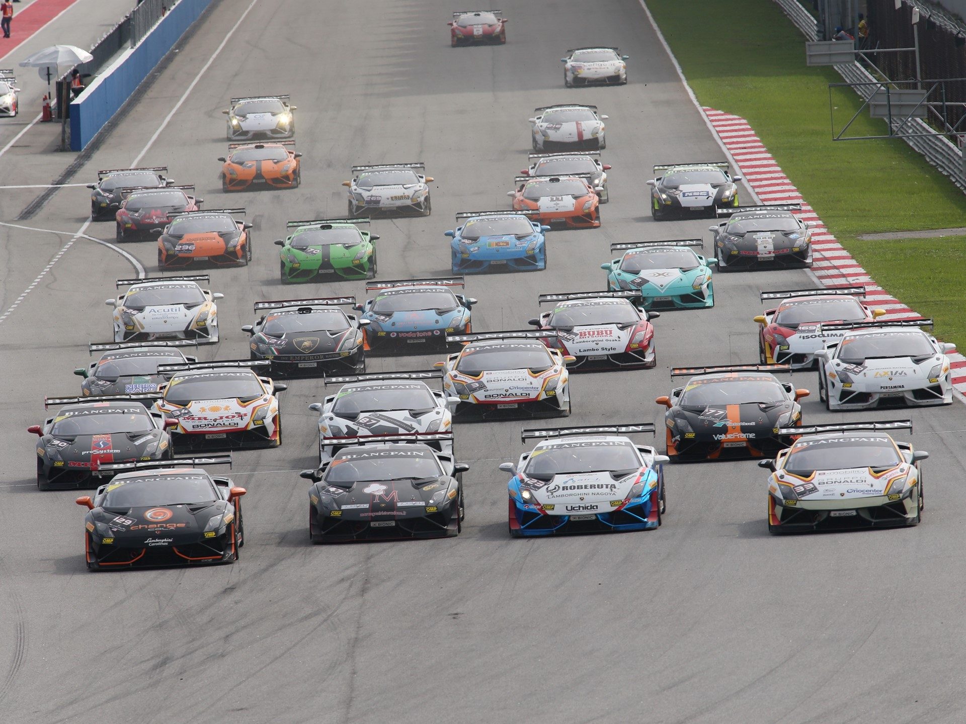 A large field of Lamborghini Gallardo Super Trofeo race cars in various liveries competing on track during the World Final