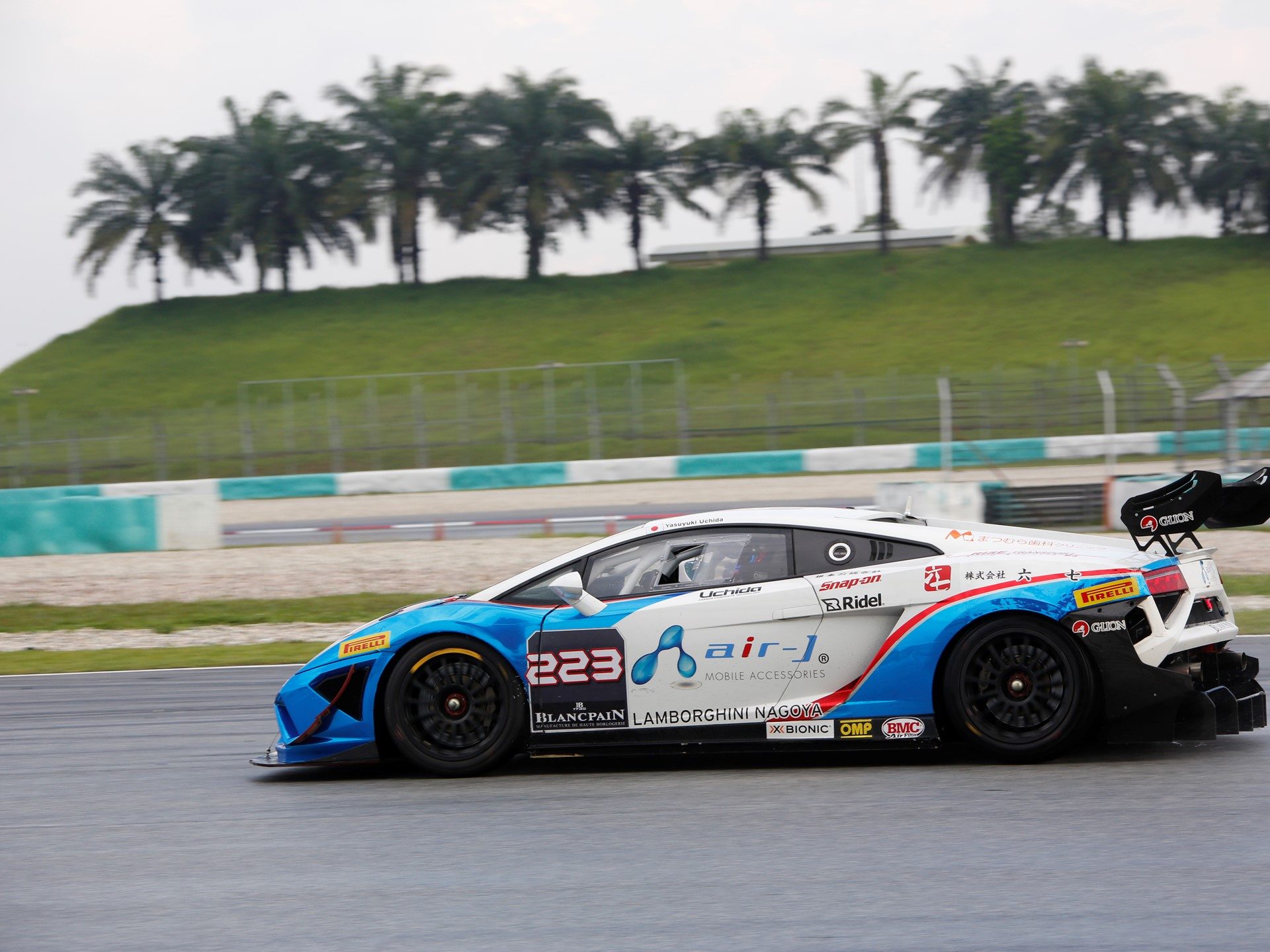 Lamborghini Gallardo Super Trofeo race car with aerodynamic body kit and large rear wing on a wet track surface