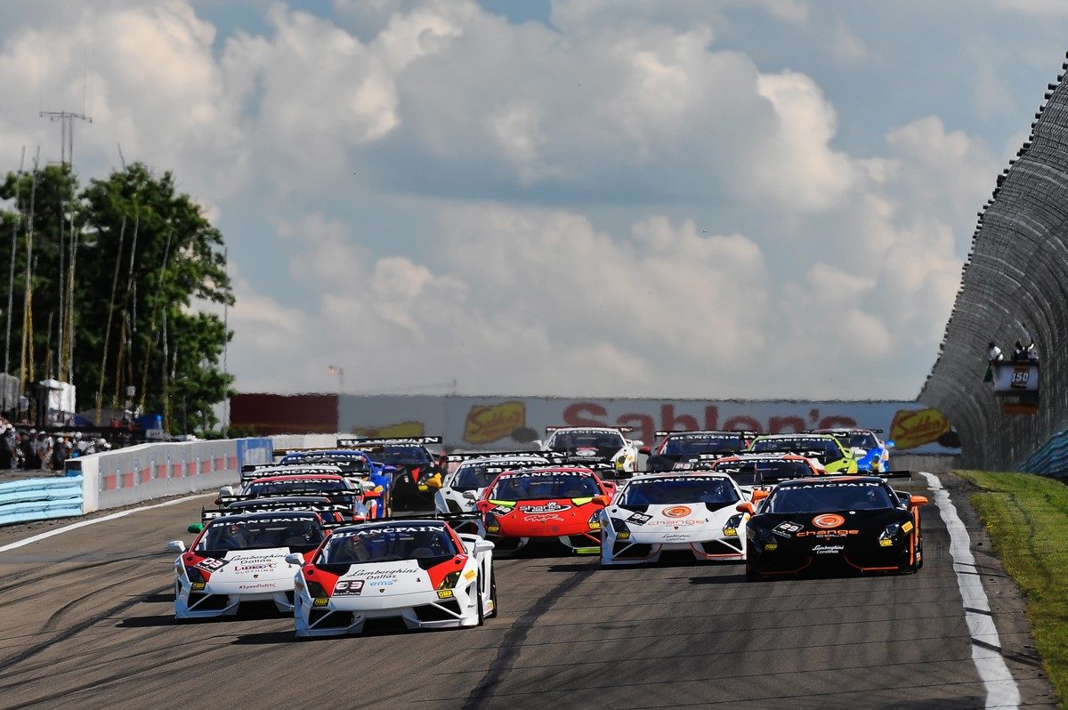 Multiple Lamborghini Gallardo Super Trofeo race cars in white, red, black, and orange liveries racing closely on track with visible rear wings and aerodynamic kits