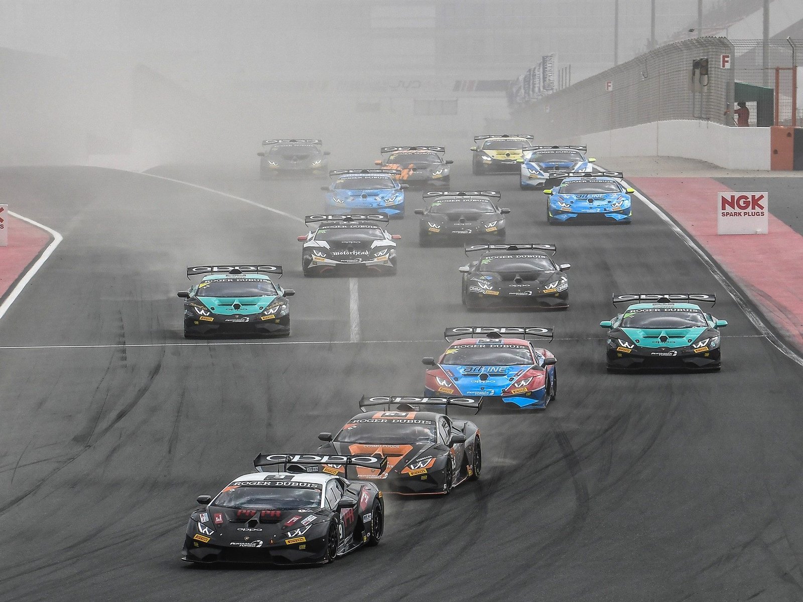 Fleet of Lamborghini Huracán Super Trofeo Evo race cars navigating a dusty track at the Dubai Autodrome during the 2019 Super Trofeo Middle East