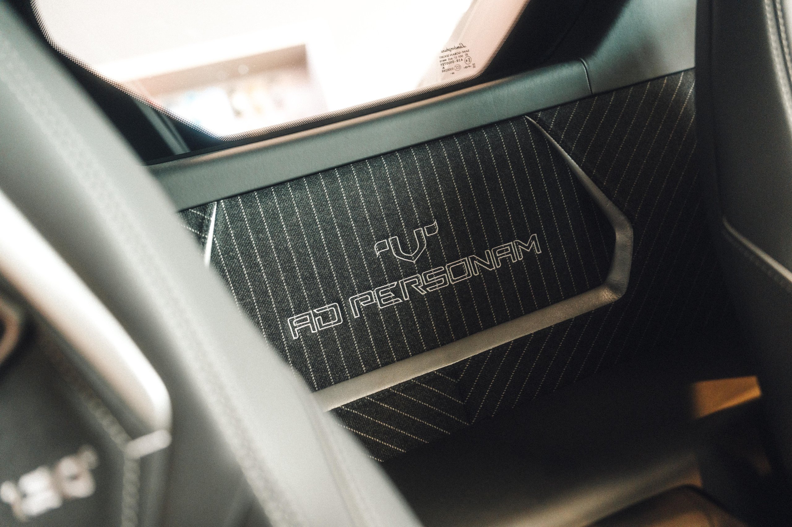 812 Hp In Verde Hydra: The Urus Se Performante Attacks Goodwood And Redefines What 'Performante' Means 11 Close-up of ad personam logo embroidered on pinstriped gessato tweed fabric panel inside the lamborghini temerario