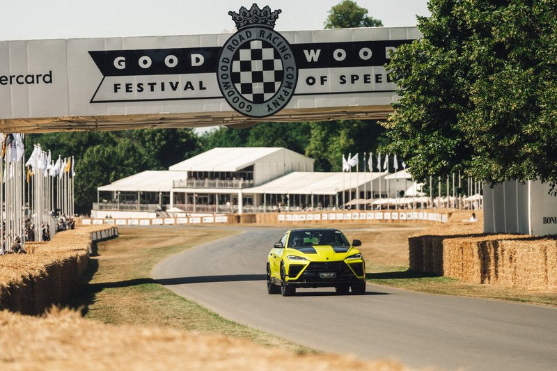 Yellow Lamborghini Urus SE Performante driving under the Goodwood Festival of Speed bridge during the hill climb