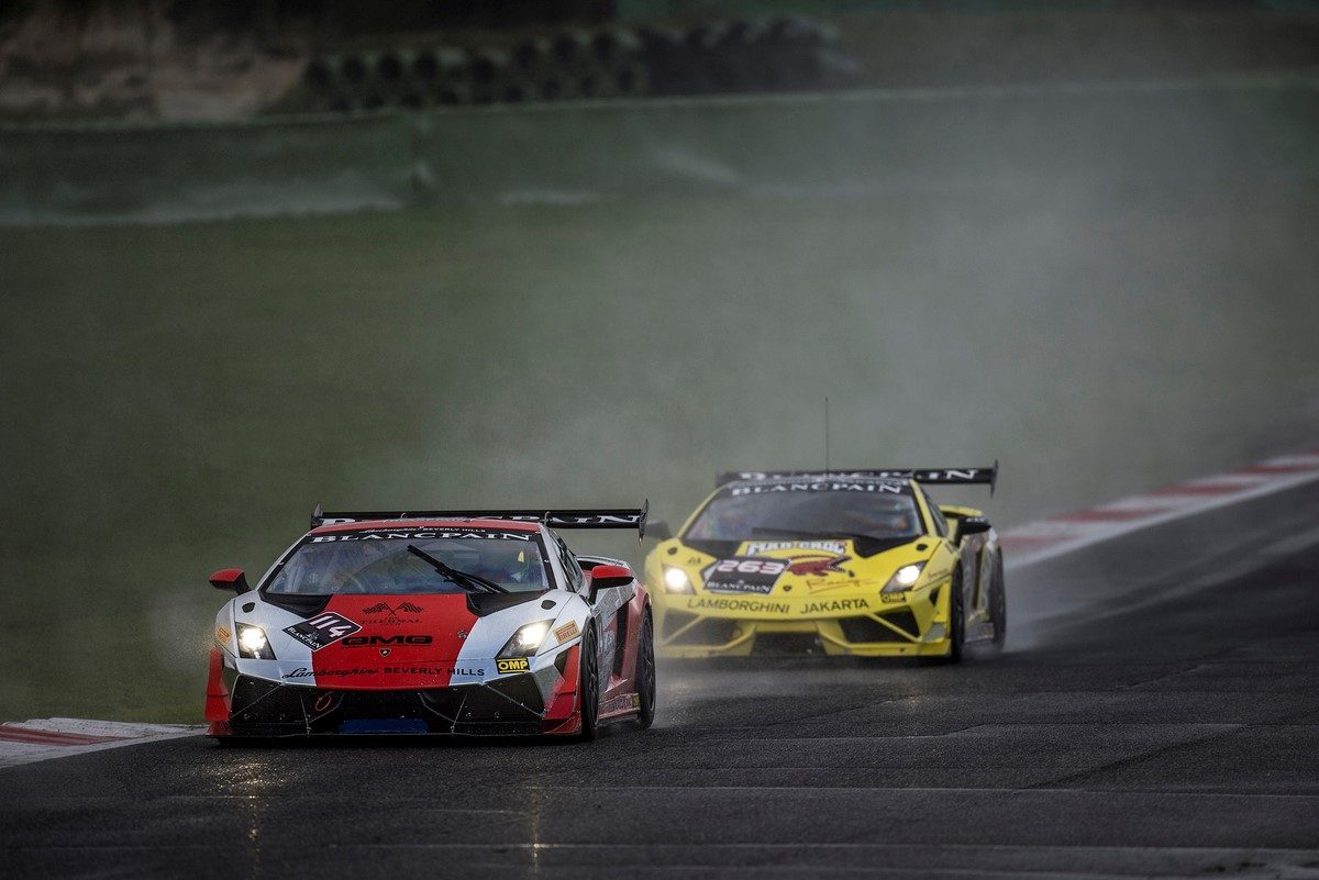 Two Lamborghini Gallardo LP 570-4 Super Trofeo race cars battling on a wet track during the Blancpain Super Trofeo series, spray flying from rain tires