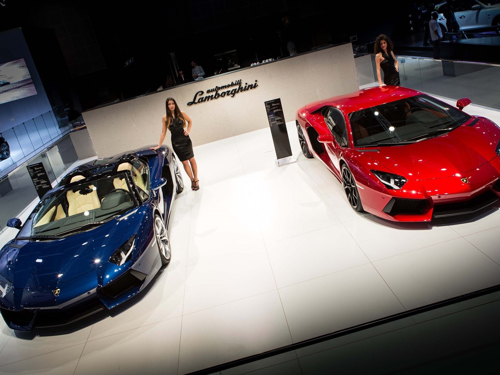 Blue Lamborghini Aventador LP 700-4 Roadster and red Aventador Coupe displayed together at the 2013 Dubai Motor Show