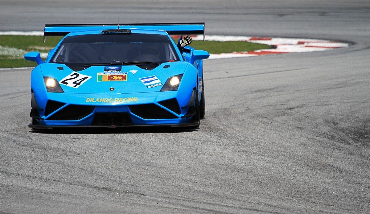 Blue Lamborghini Gallardo GT3 race car number 24 cornering on a racetrack with its large rear wing and carbon fiber aero elements visible