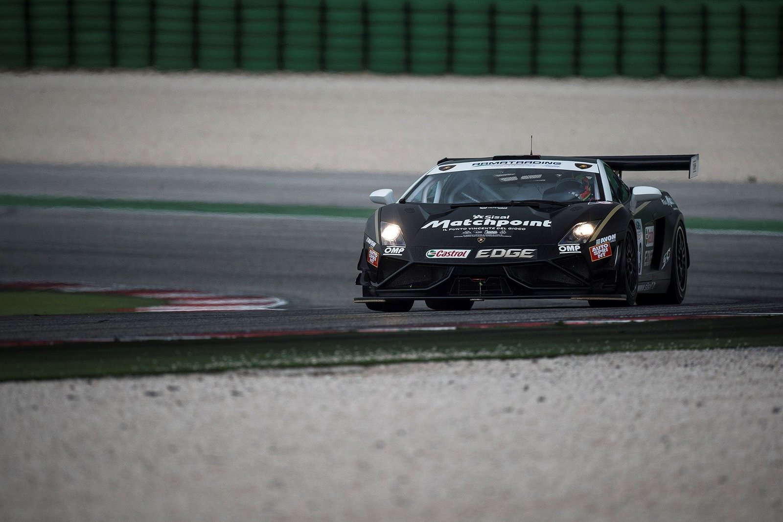 Black Lamborghini Gallardo GT3 FL2 race car at speed on circuit with prominent rear wing and front splitter visible