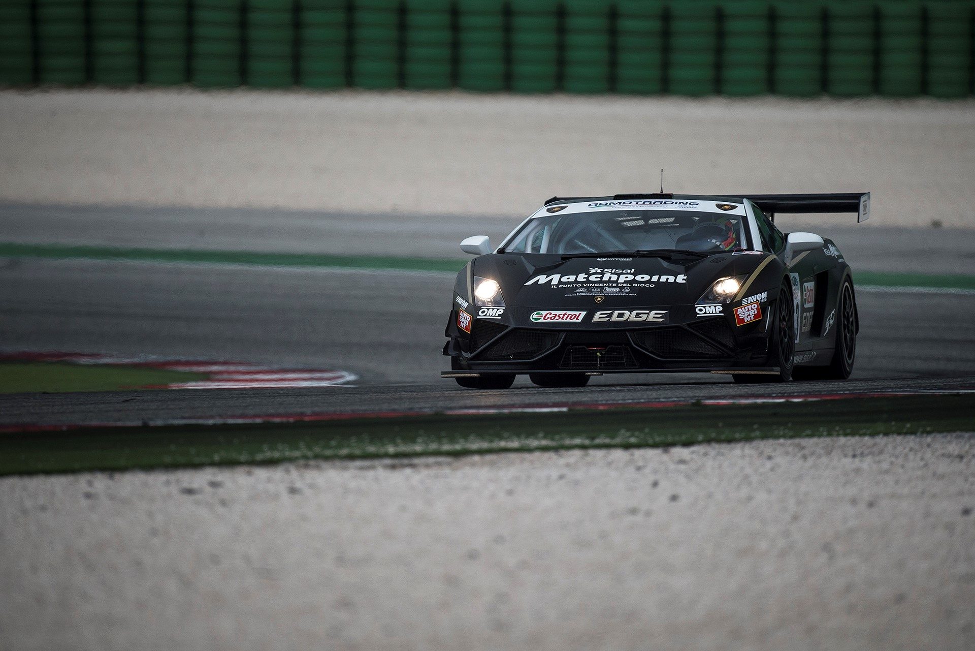 Black Lamborghini Gallardo GT3 FL2 race car at speed on circuit with prominent rear wing and front splitter visible
