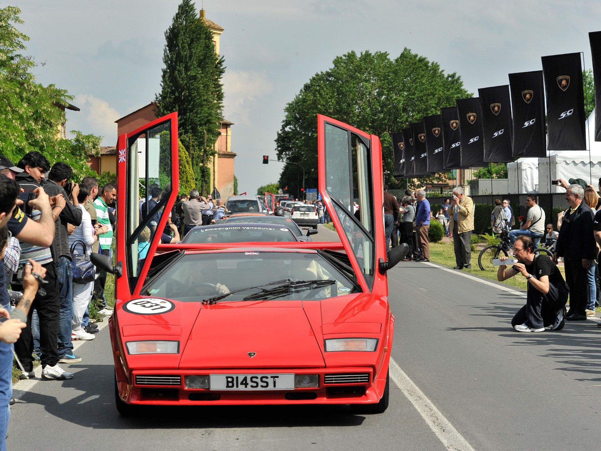 Red Lamborghini Countach with scissor doors open surrounded by spectators at the 50th Anniversary Grande Giro event