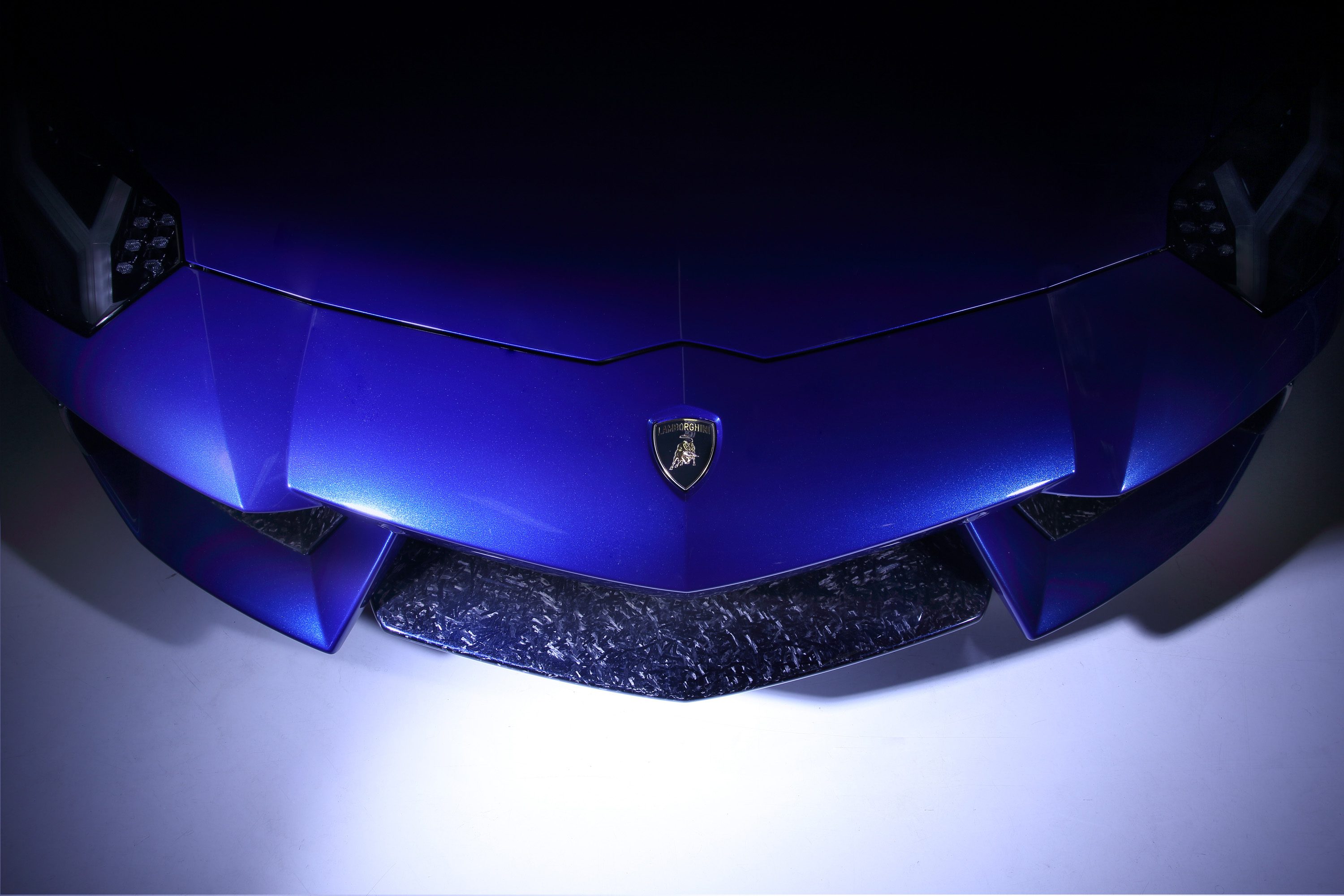 Close-up of the Blue Sideris Aventador front bumper showing Lamborghini emblem and carbon fiber accents