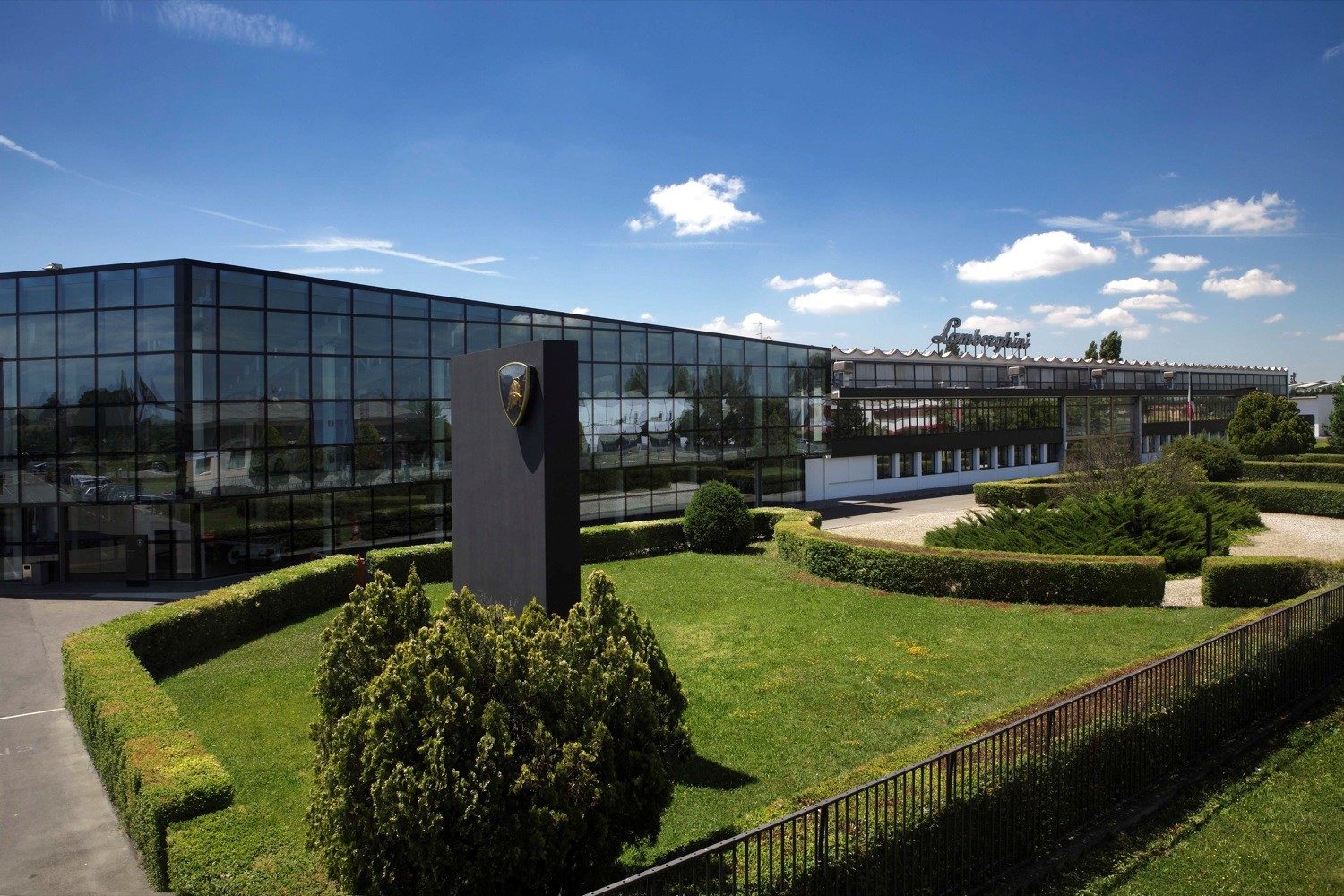 Lamborghini headquarters in Sant'Agata Bolognese with the iconic bull emblem monument under a clear blue sky