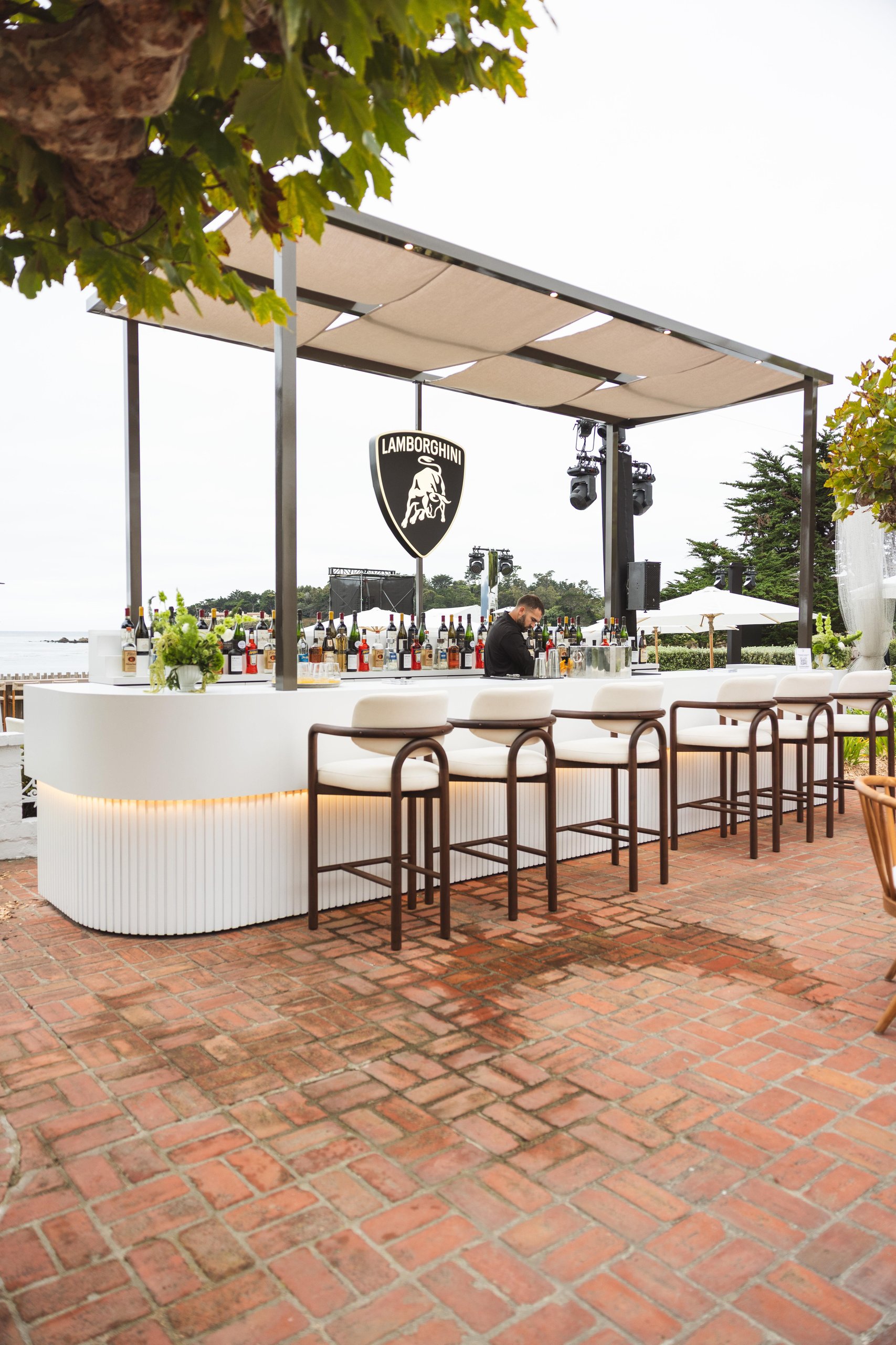 Outdoor bar at the Lamborghini Villa featuring a white counter, illuminated Lamborghini shield logo, and ocean views