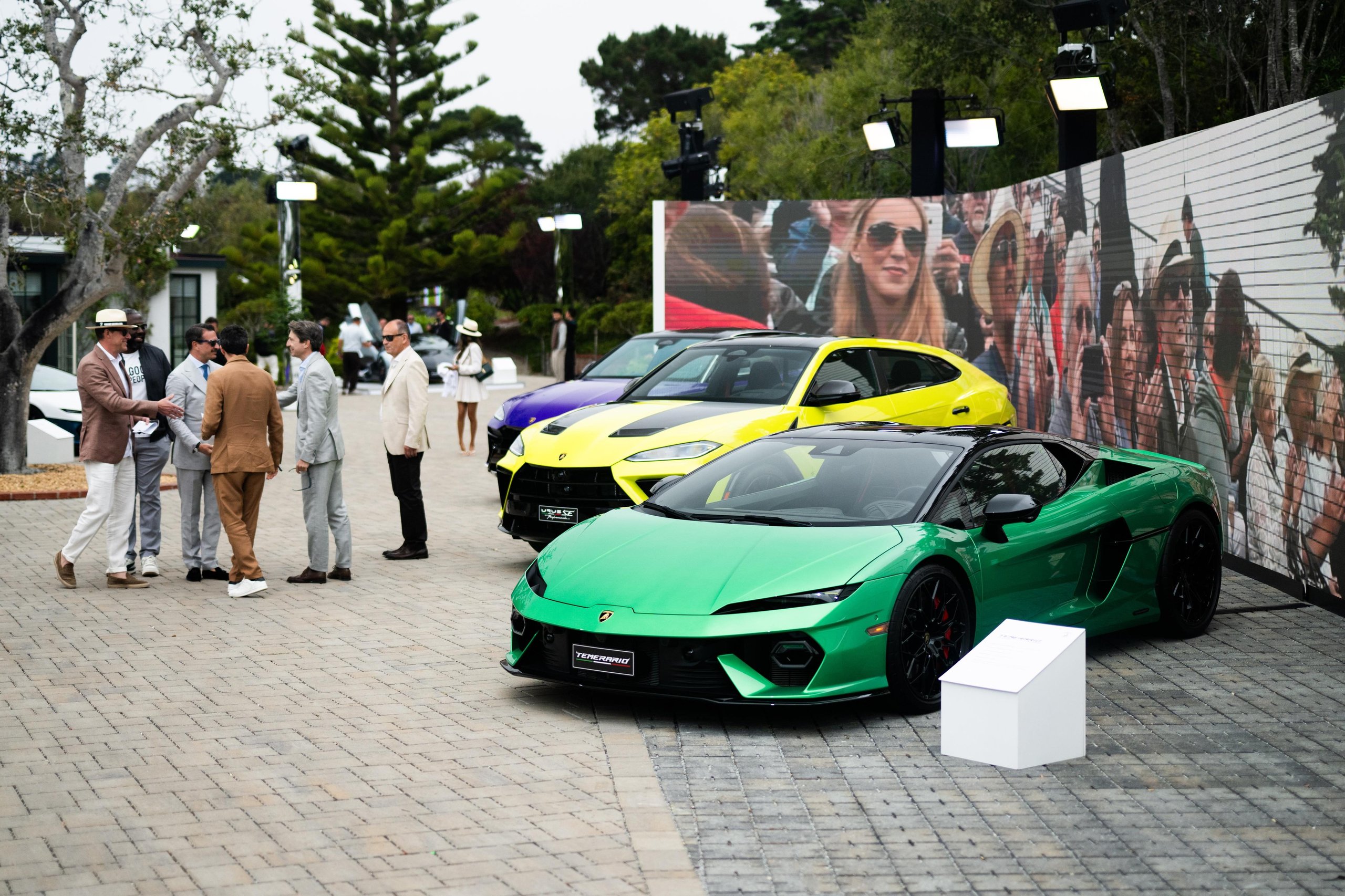Green Lamborghini Temerario displayed alongside a yellow Urus with guests in the background at the Lamborghini Villa