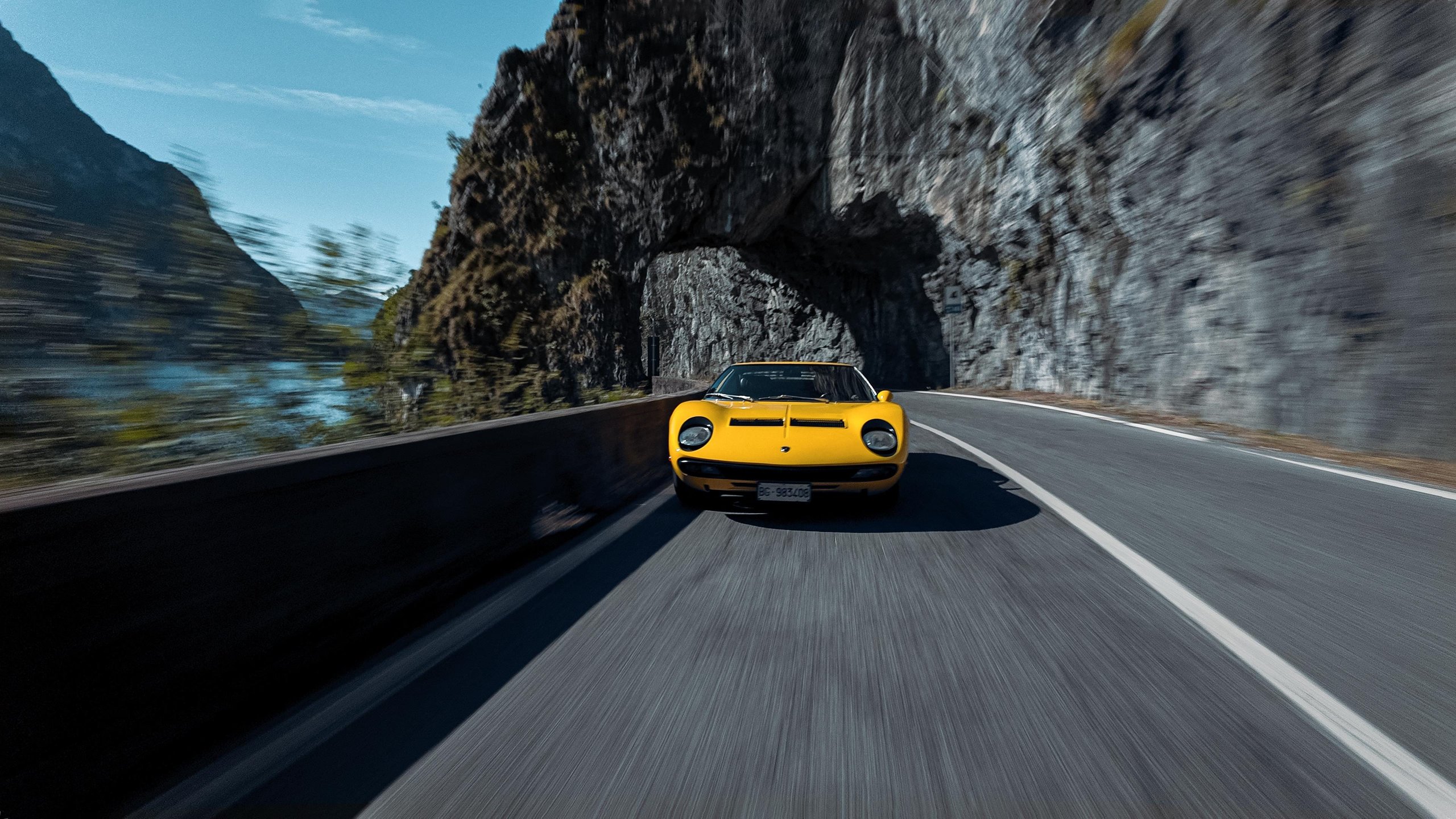 Lamborghini'S Miura Sv At 55: Why An Astronaut Behind The Wheel Says More Than Any Spec Sheet 3 Yellow lamborghini miura sv at speed on a winding lakeside road with motion blur and rocky cliffs
