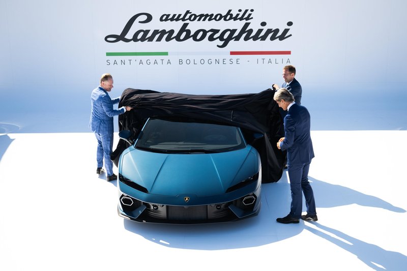 Lamborghini executives unveil the matte blue Temerario at its Monterey Car Week 2024 world premiere, pulling a black cover off the car on the white Lamborghini stage