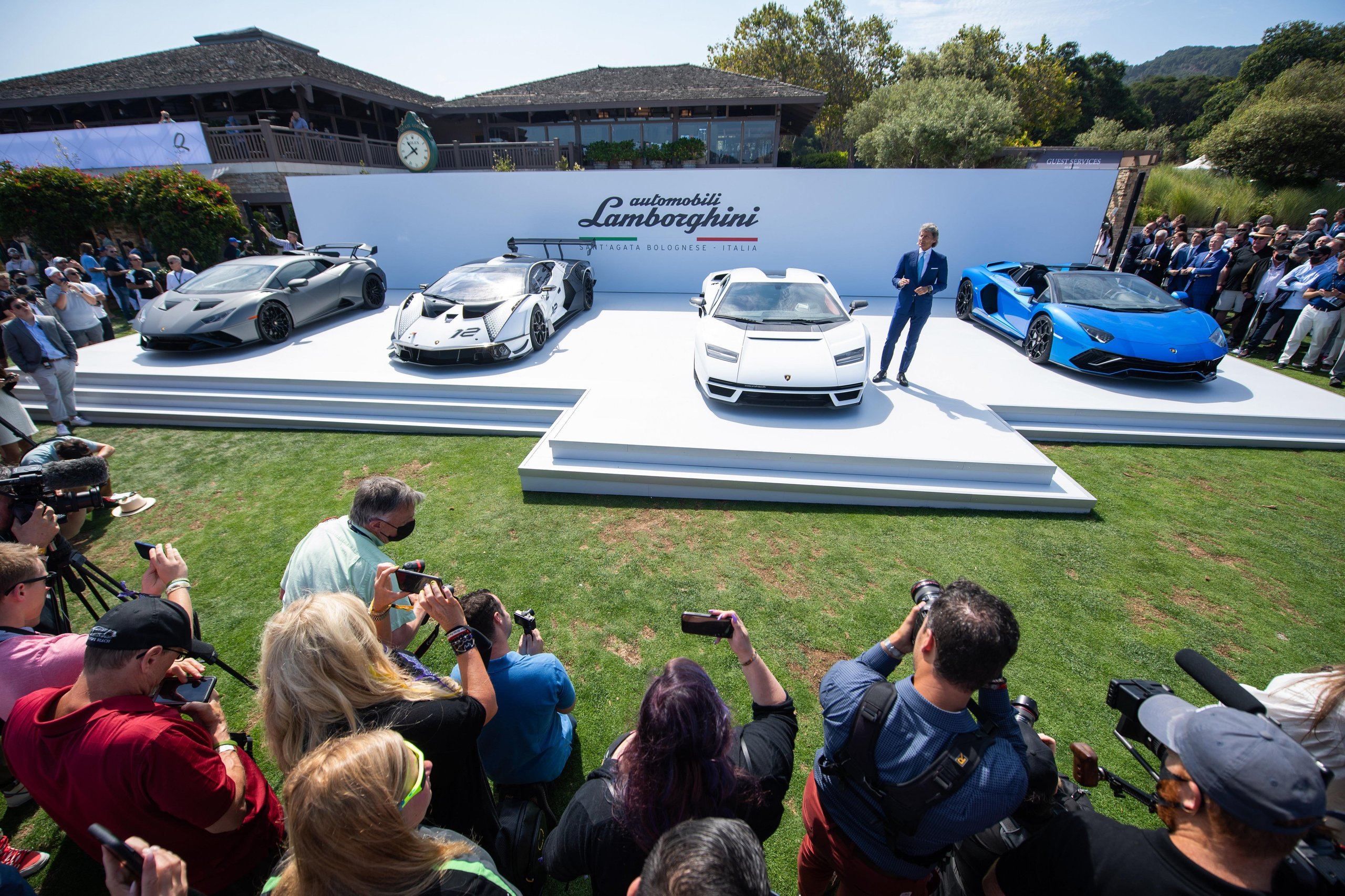 Lamborghini stage at the Countach LPI 800-4 world premiere, Monterey Car Week 2021: a grey Huracán STO, the Essenza SCV12, the white Countach LPI 800-4, and a blue Aventador Roadster before a crowd of spectators