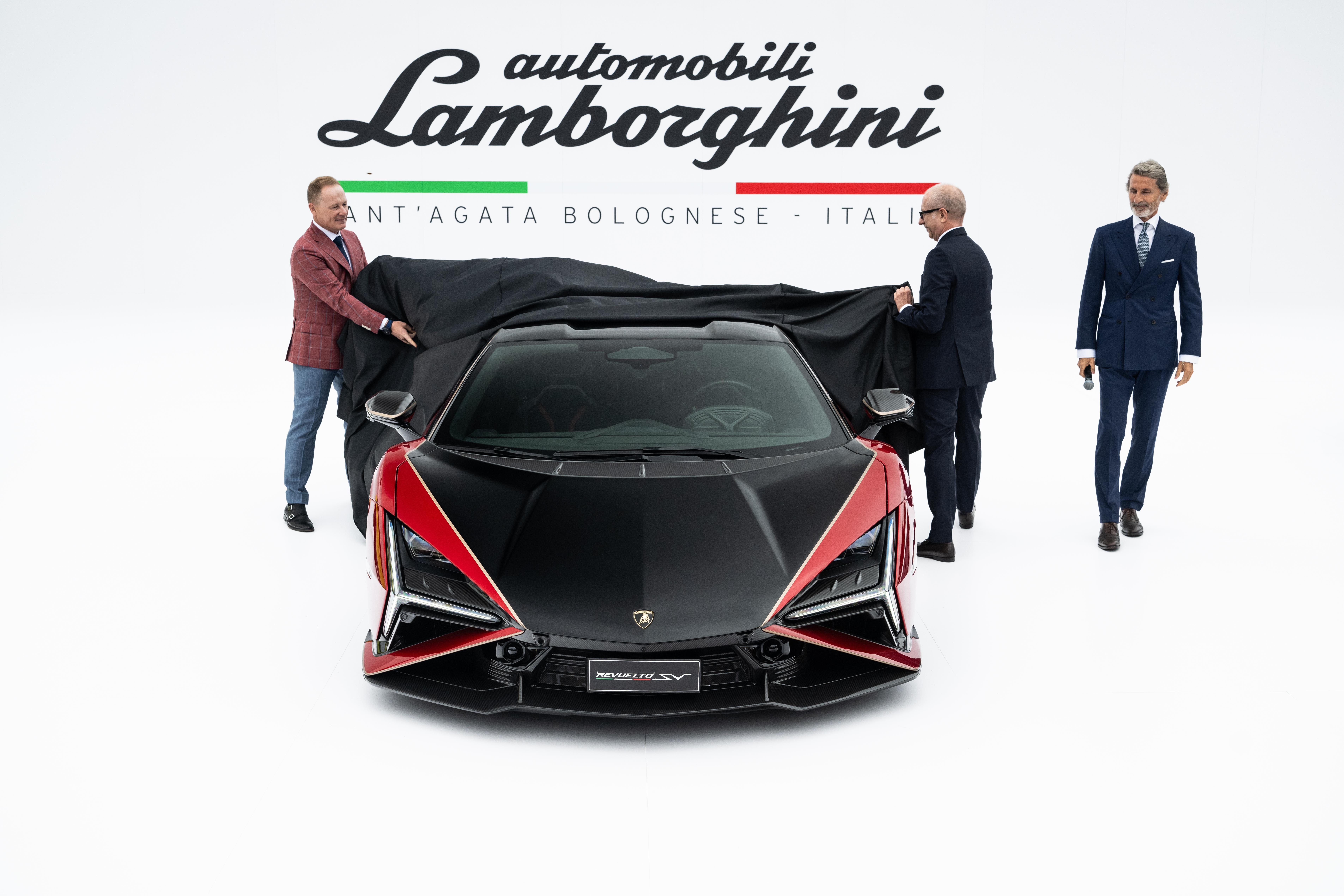 Three men unveil the black and red Lamborghini Revuelto SV on a white stage at The Quail