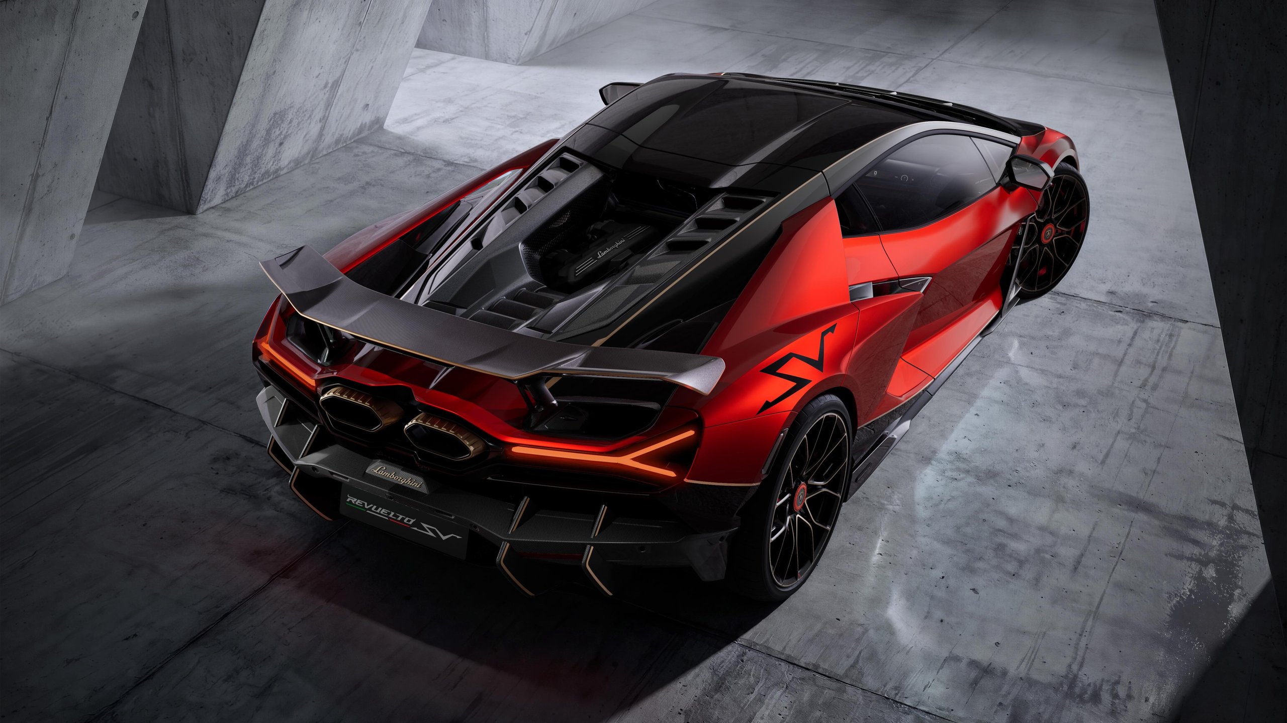 Rear three-quarter view of the red and black Lamborghini Revuelto SV showing exposed engine bay, rear wing, and gold accents