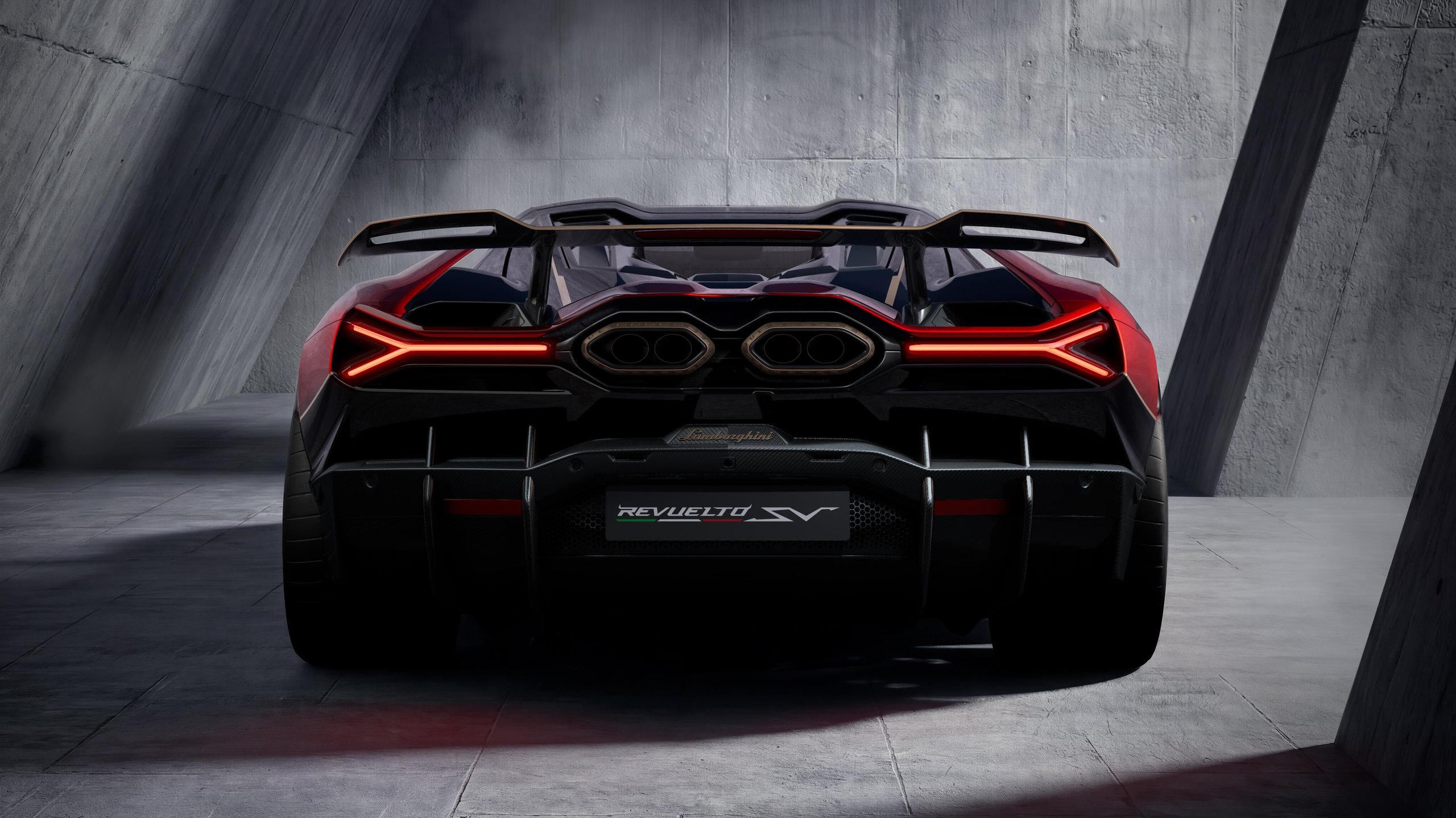 Rear view of the red and black Lamborghini Revuelto SV showing rear wing, Y-shaped taillights, and diffuser with red accents