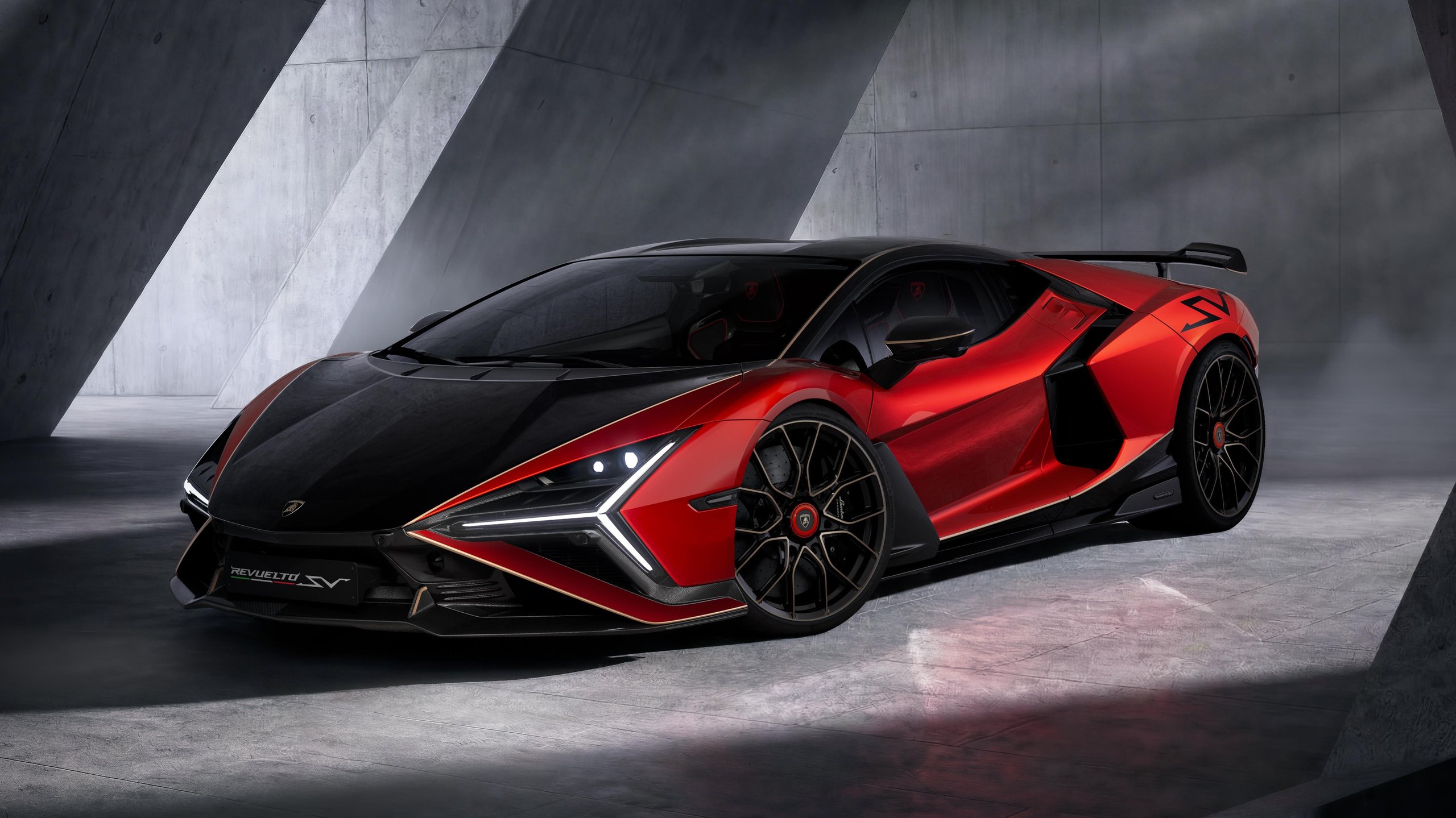 Red and black Lamborghini Revuelto SV in a studio, showcasing aggressive aerodynamic design and two-tone paint