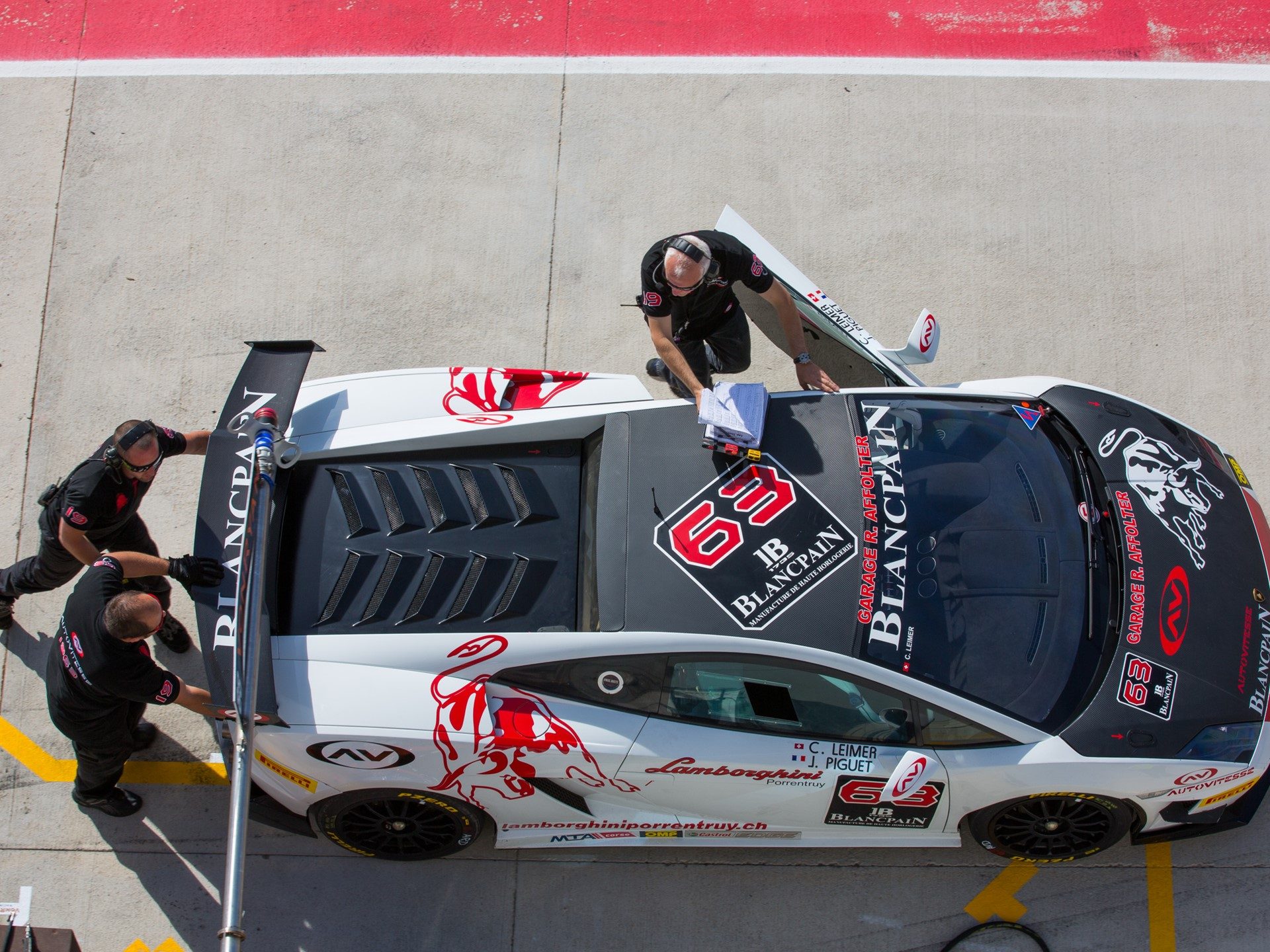 Overhead view of a white Lamborghini Gallardo Super Trofeo race car in the pit lane with crew members working around it during the 2013 Monza round